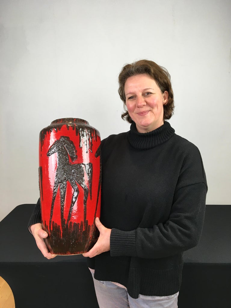 1960s Red Fat Lava vase with horses.
This Western Germany Art Pottery Vase by Scheurich 
has the color red with dark brown, black horses on.
The design is embossed or with relief on this vintage red vase.
Inside the vase beautiful color blue.
The