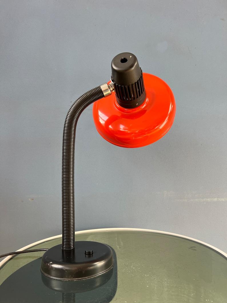 Red space age desk lamp with flexible arm. The arm and shade can be positioned in any way desirable. The lamp is made out of metal and plastic. The lamp requires one E27/26 (standard) lightbulb and currently has an EU plug.

Additional