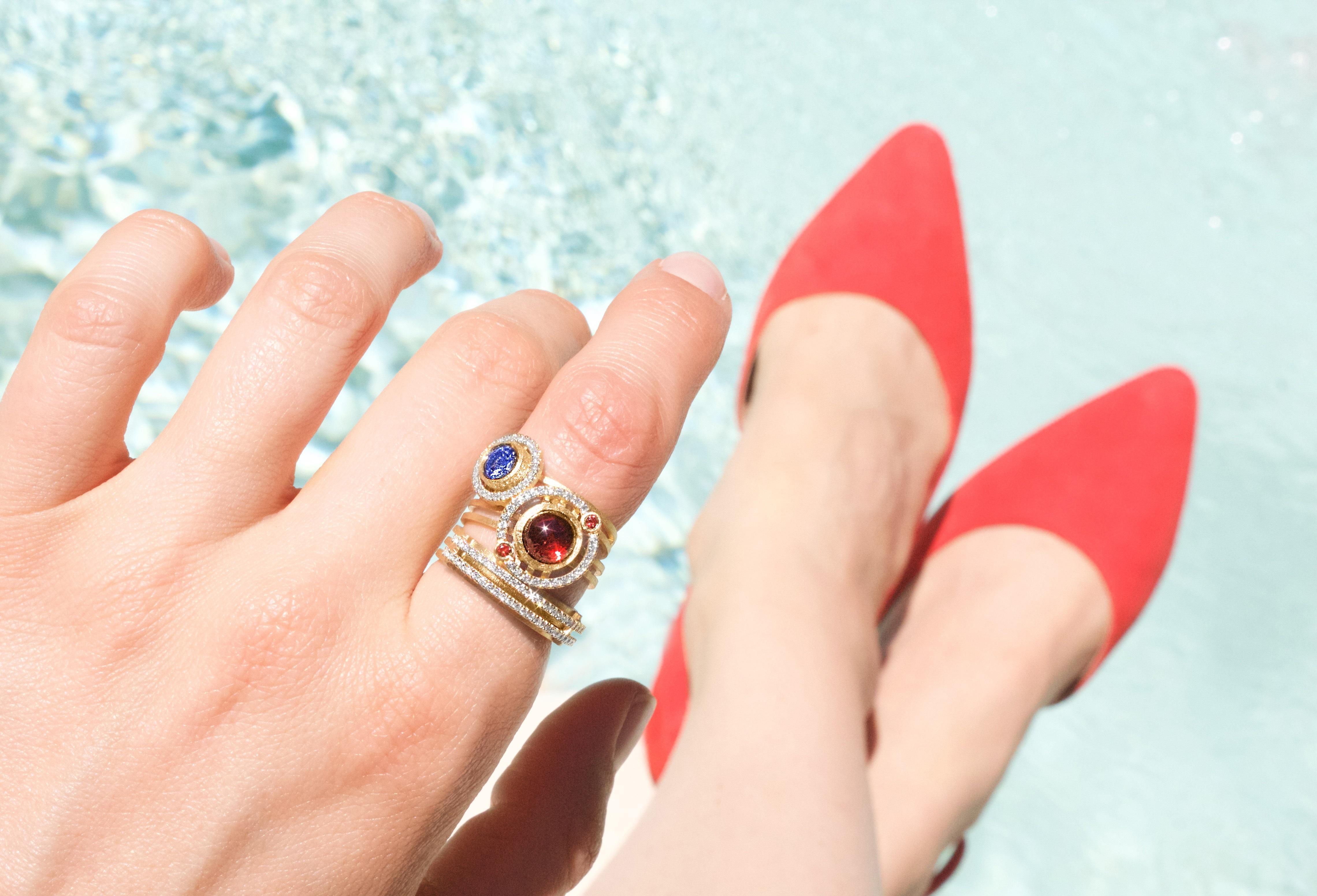Nova Ring intricately handcrafted by London-based jewelry artists Shimell and Madden in a signature reflective-finished 18k yellow gold showcasing an extraordinary 7mm cabochon-cut deep red garnet, accented by two bezel-set orange sapphires and 0.13