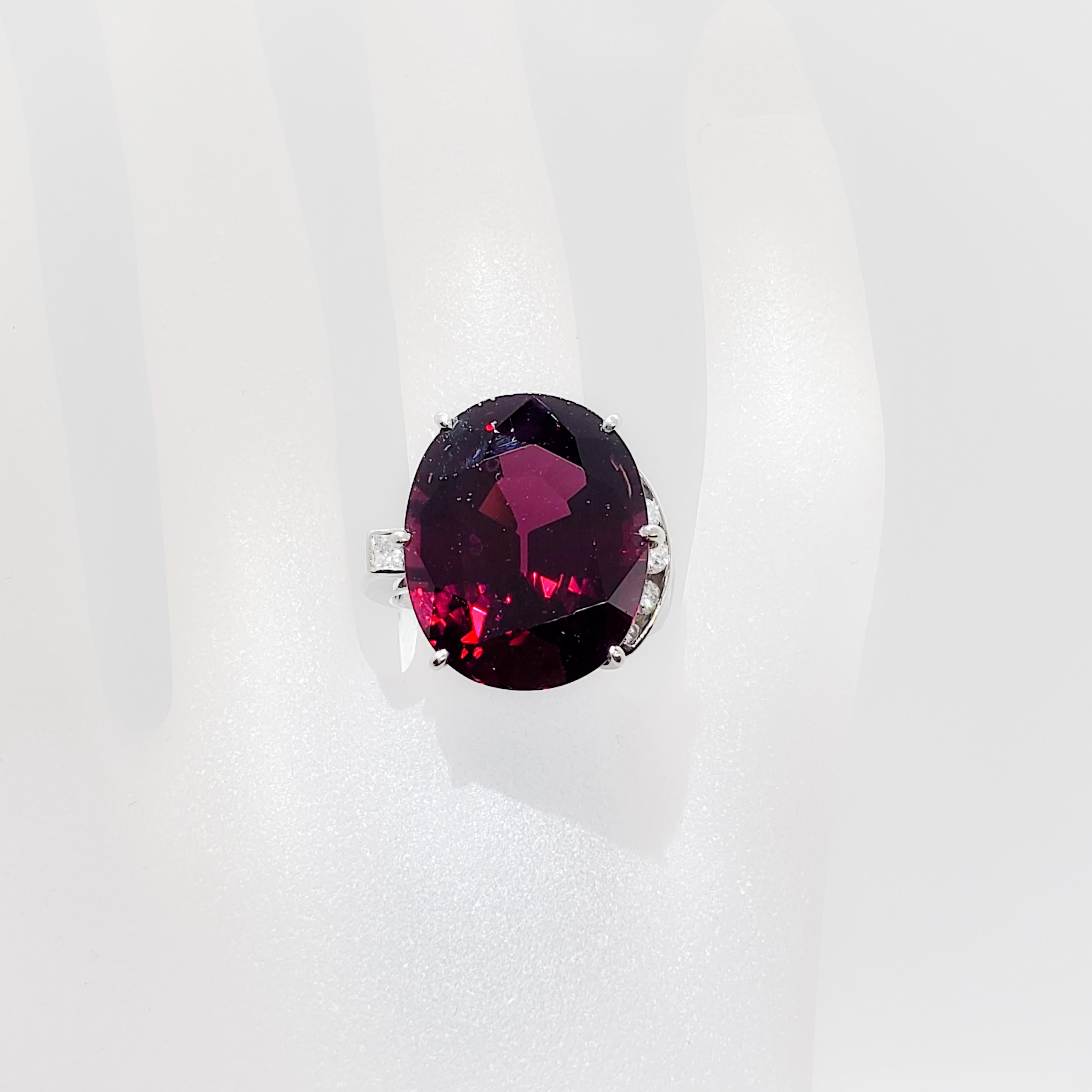 Stunning red garnet oval with deep color and beautiful crystal weighing 23.52 cts.  Six white diamond rounds and squares of good quality weighing 0.27 cts. Handmade mounting in platinum.  Ring size 7.25.  Estate piece in excellent condition.