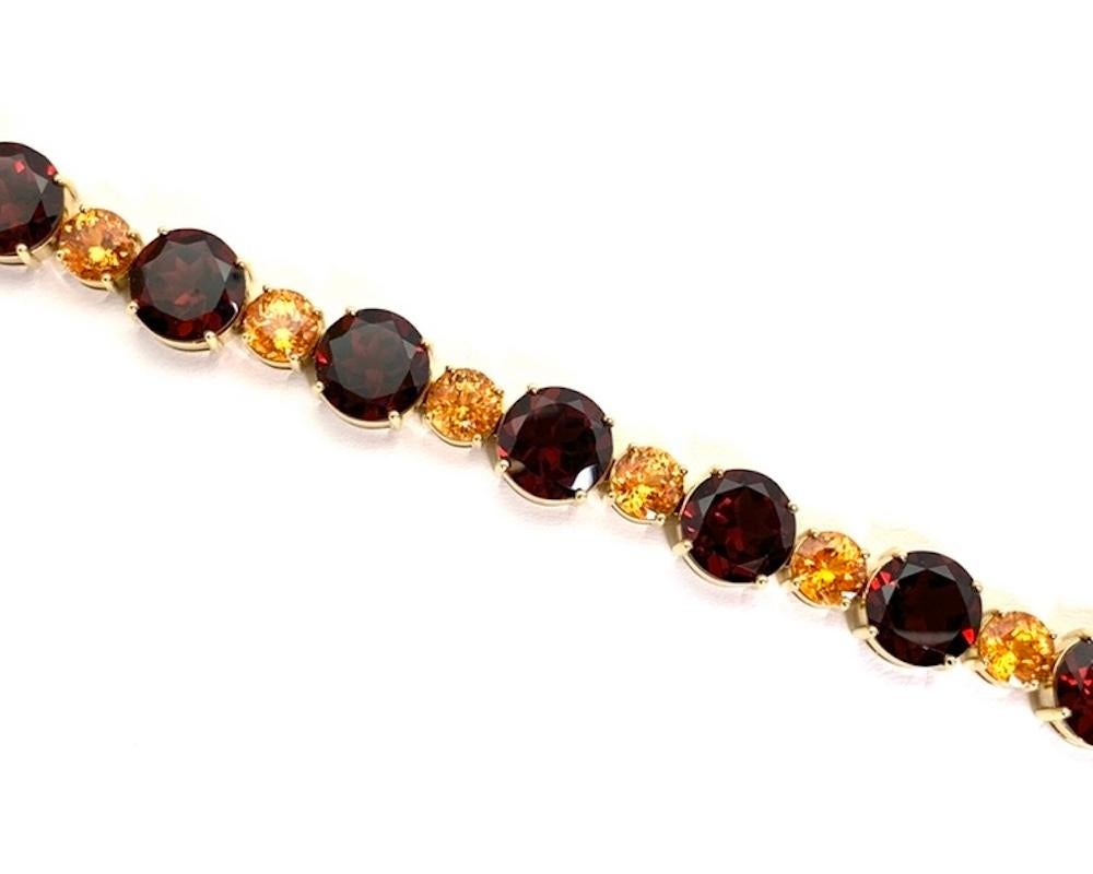 This stunning tennis-type bracelet features over 54 carats of beautiful garnets set in 18k yellow gold! Rich red garnets are paired with fiery orange spessartite garnets in alternating blocks of color and size. This combination creates a bold,