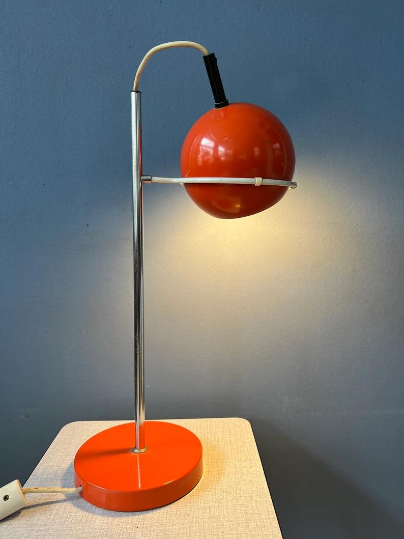 Lampe de table de l'ère spatiale à globe oculaire rouge de la marque néerlandaise Gepo. L'abat-jour en métal rouge peut être positionné de la manière souhaitée dans l'anneau métallique. La lampe nécessite une ampoule E27 et dispose actuellement