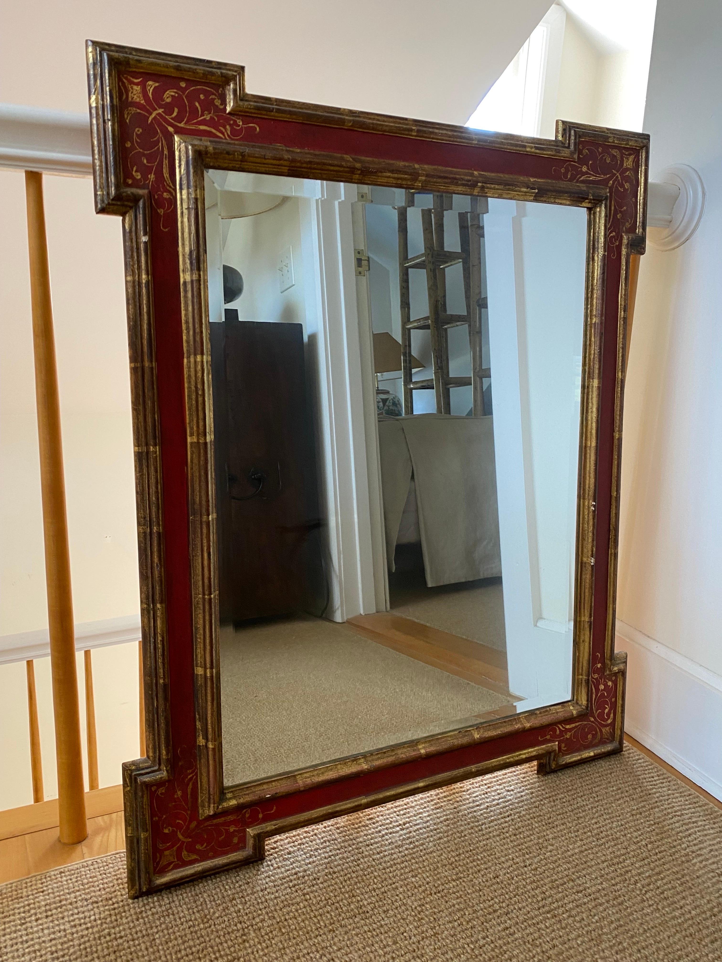 Red gilded framed mirror, late 20th century.

This beautifully crafted mirror has a rectangular frame with angular protruding corners and gilded molding. At the corners of the frame, you can find small delicately painted floral leaves and stems. The