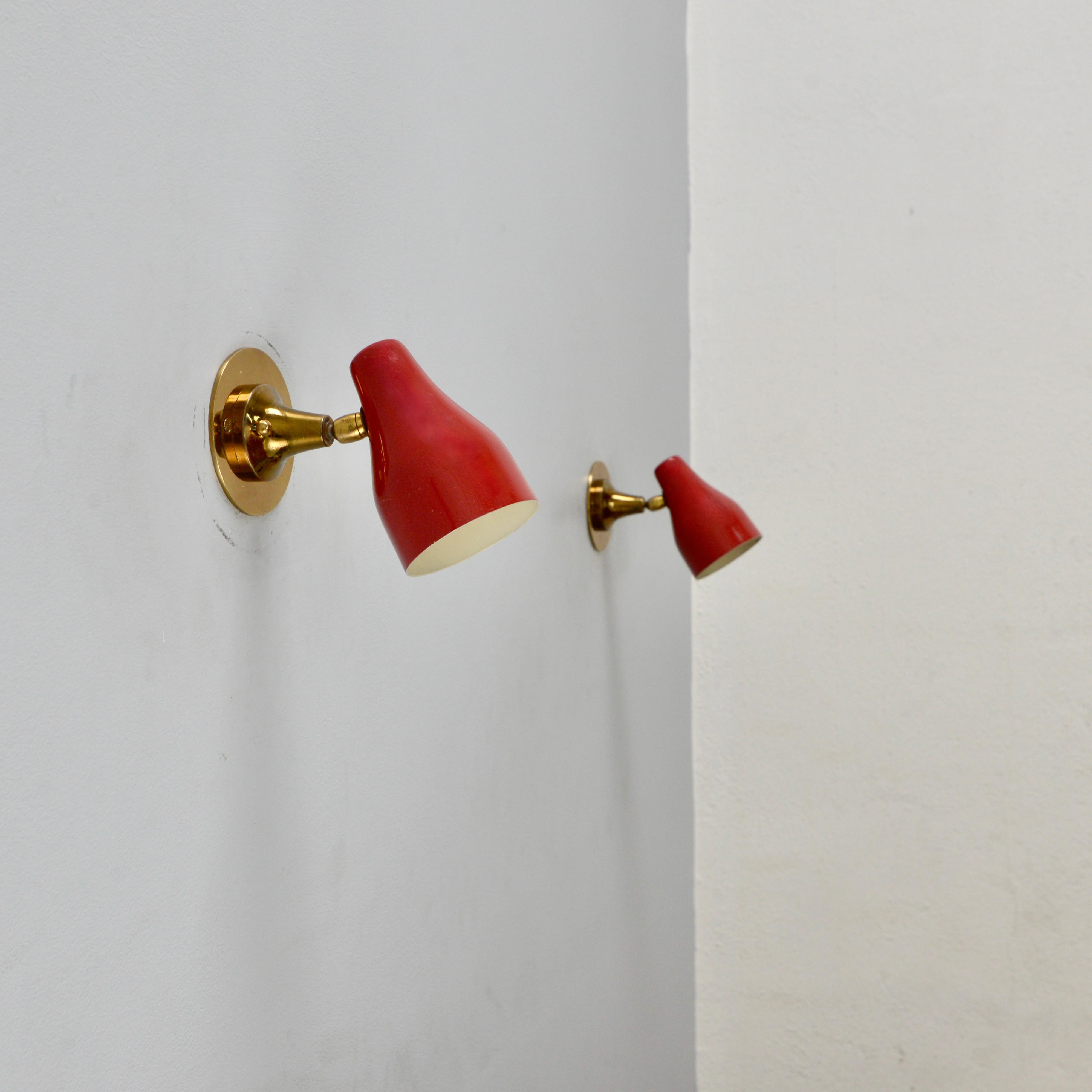 Pair of red directional Mid-Century Modern Giuseppe Ostuni sconces from Italy. Original paint and patina brass. Partially restored wiring of a single E12 based socket per sconce. Maximum wattage 40 watts per sconce. Back plate has 2 3/4