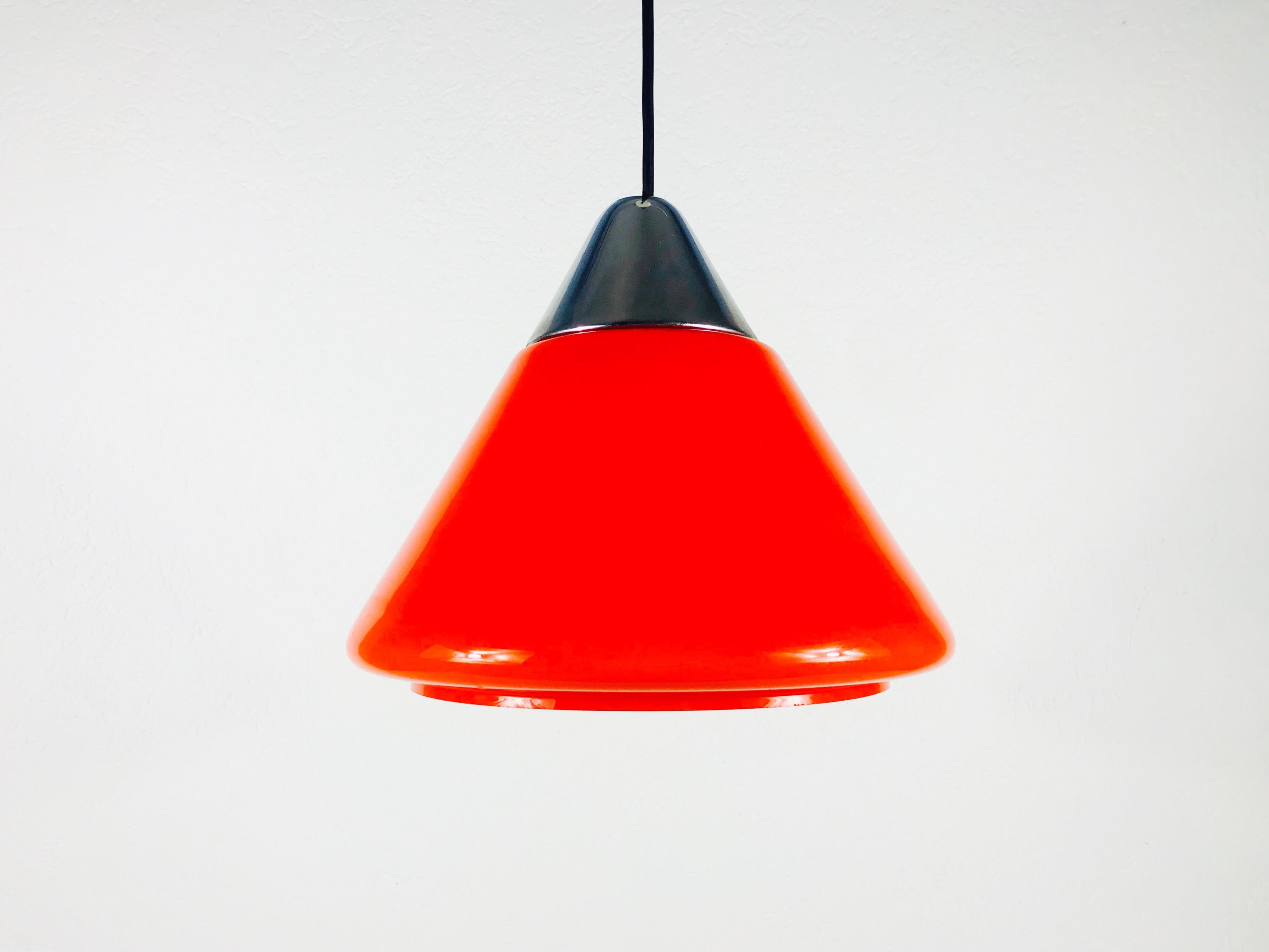 A red hanging lamp by Peill and Putzler made in Germany in the 1970s. It has a red glass shade in the shape of a cone. The top part of the glass shade is chrome aluminium.

Measurements:

Height 55 cm

Diameter 31 cm

The light requires one