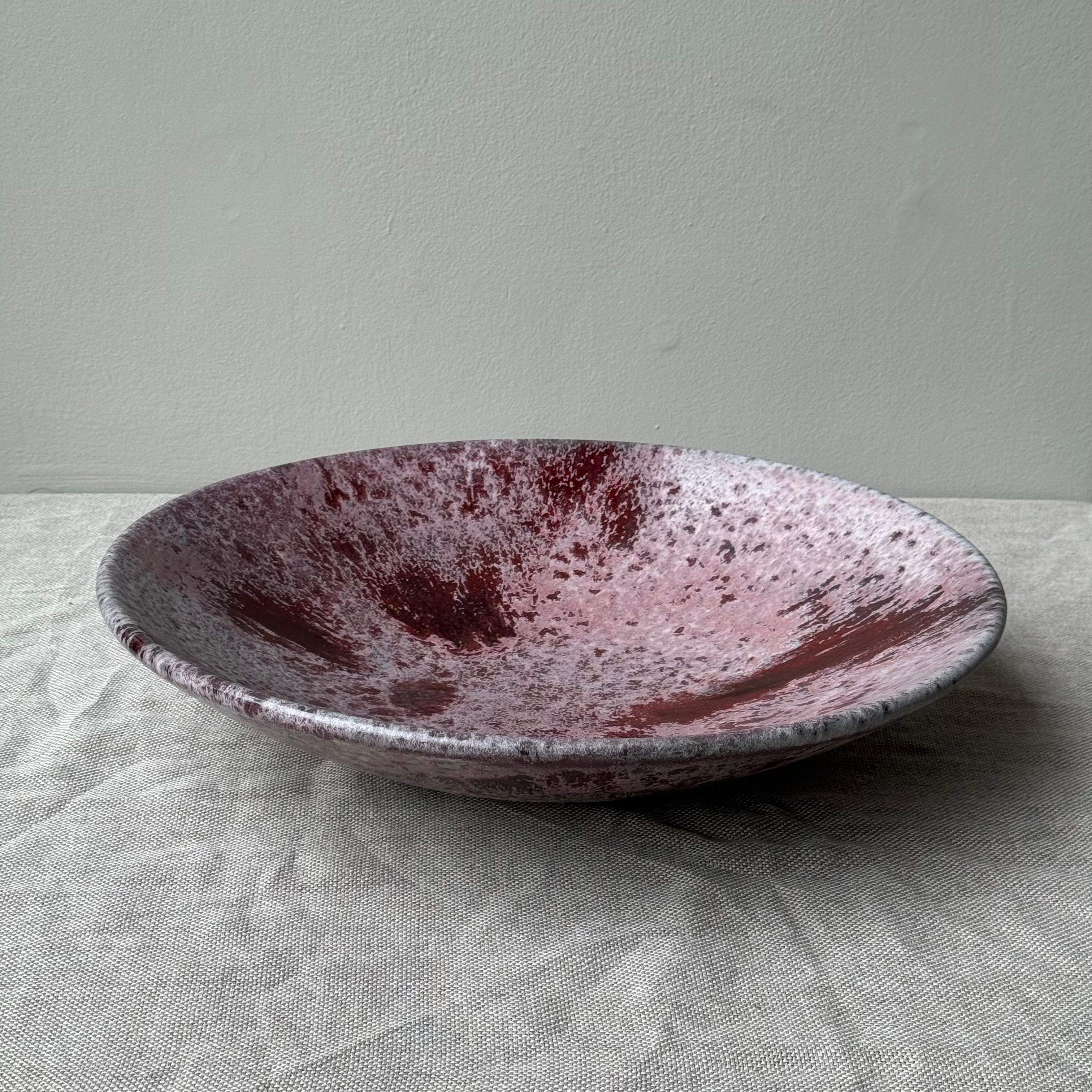 A stoneware platter made and designed in Denmark by K H Würtz. 

Testament to the complex glazes of the Danish studio, this vivid red glazed platter contains a constellation of luminous flecks of colour, from deep burgundy to the lightest of