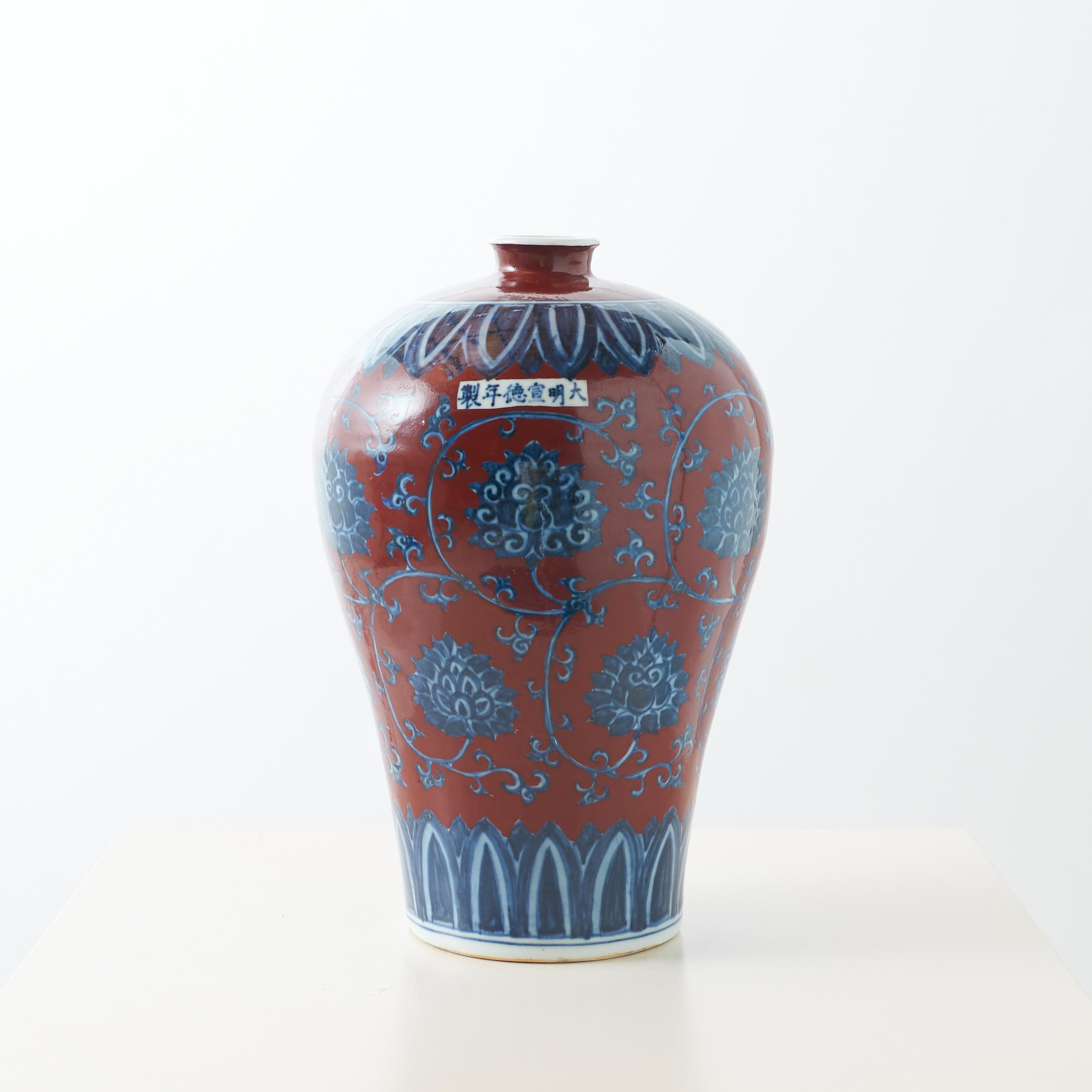 Vase en porcelaine émaillée rouge avec design floral

Vase décoratif en porcelaine de Chine en forme de prune, présentant un motif floral bleu et blanc sur fond rouge, marqué 製年德宣明大 sur le corps, signifiant 