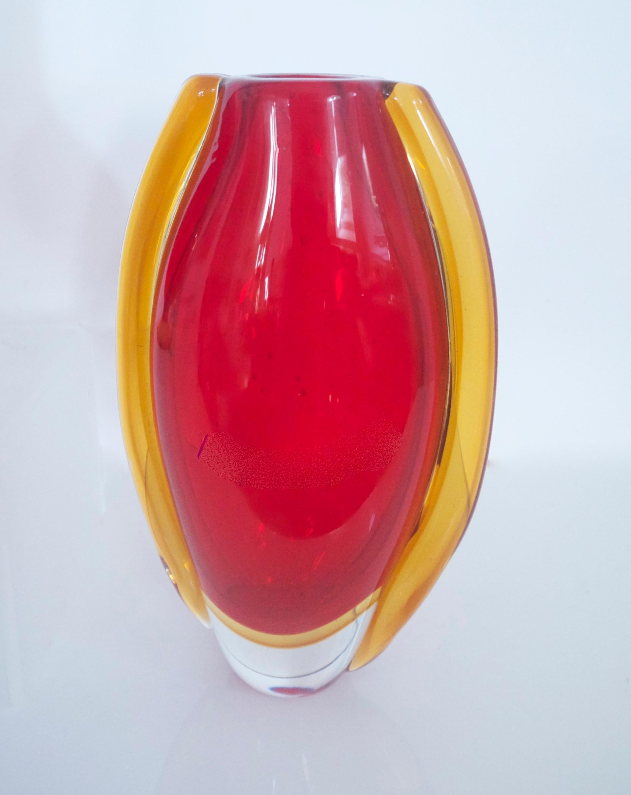 This red glossy pencil vase was designed by Carlo Morretti in the mid-1960s. It is made of Murano glass and is colored red with a yellow foot. It is of a Space Age design. With it, we have a Murano vase in the same colour way red with applied
