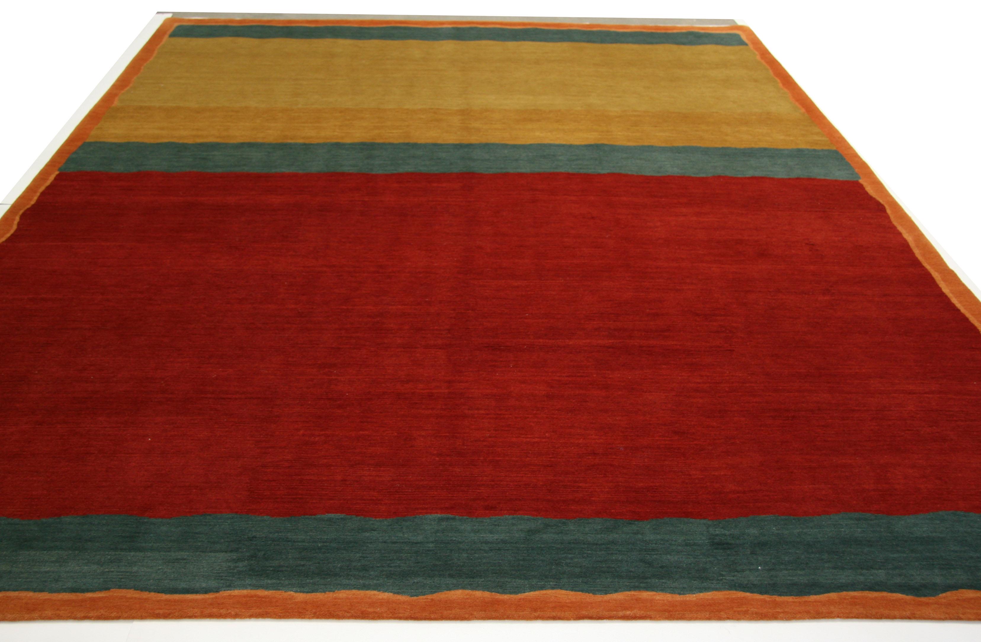 The bright colorful look of a Kilim in a pile rug! Bold red, gold, tan, and blue-gray add an instant color pop. An ideal piece for the contemporary casual family room or other lived-in space. 

Hand knotted in Nepal using wool dyed with natural