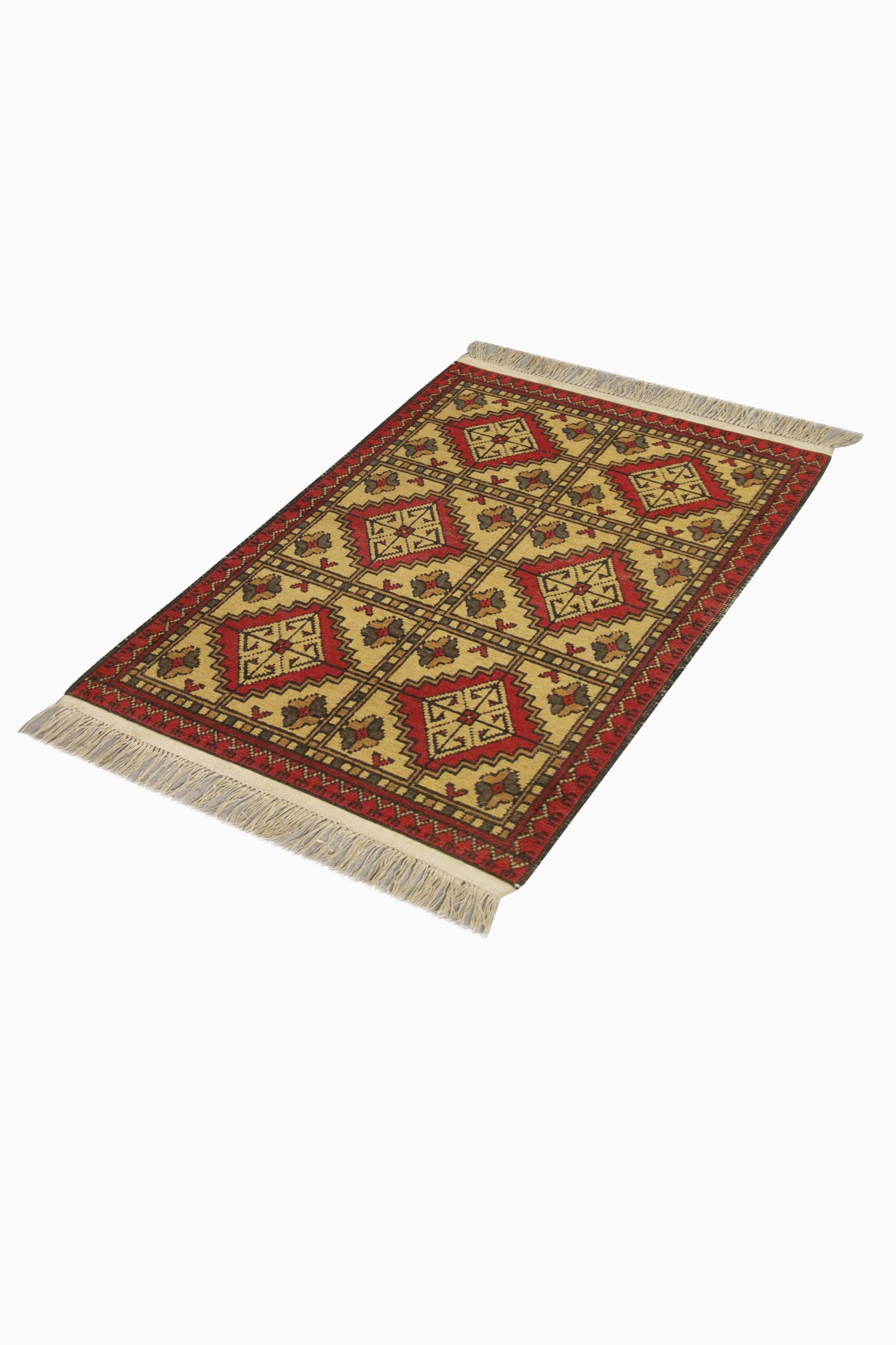 This bold wool area rug is a handwoven carpet constructed in the late 20th century. The design features a repeating geometric pattern woven in a simple beige, red, gold yellow and blue colour palette. The colour palette and geometry in this carpet