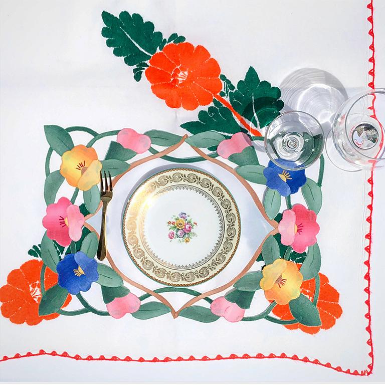 White table cloth or table runner with handstitched floral embroidery. The piece features bright red hibiscus flowers with greenery. Edges are handstitched or crocheted with matching red yard. A beautiful piece for summer dinner parties.