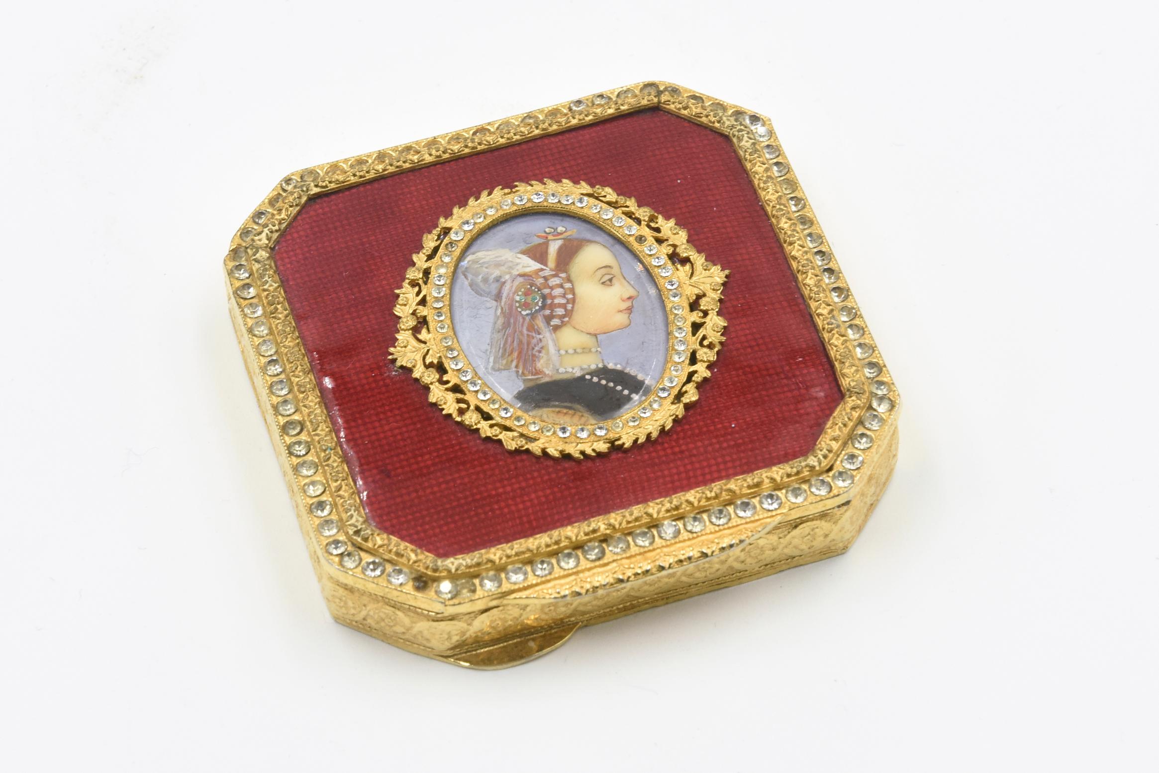 Square guilloche enamel gilt jeweled compact with hand painted portrait of a period lady.
This gold tone metal compact with red guilloche enamel and lovely hand painted lady with an Elizabethan hair piece, green dress with amazing hand painted