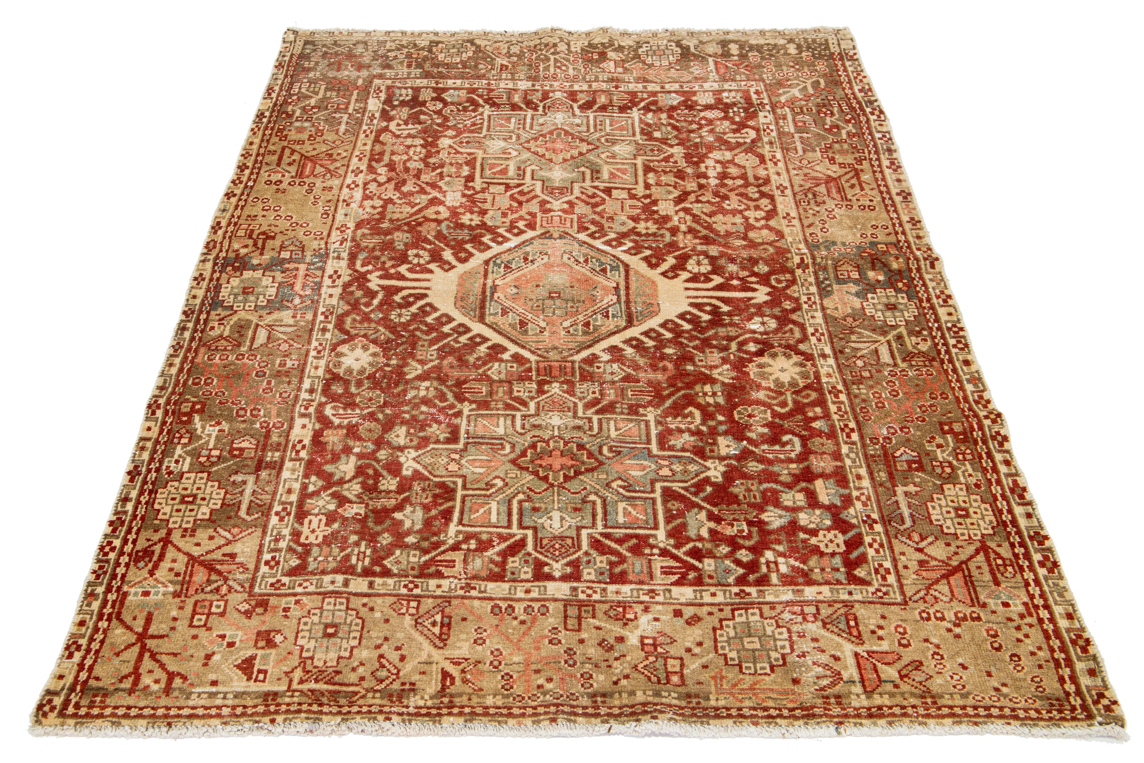 This antique Persian Heriz rug is made with hand-knotted wool. The rust-red field showcases a captivating medallion pattern adorned with beige, peach, and brown shades.

This rug measures 4'7