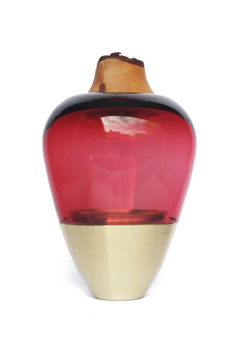 Red India Vessel I, Pia Wüstenberg.
Dimensions: D 20 x H 38.
Materials: glass, wood, metal.
Available in other metal: brass, copper, copper patina.

Handmade in Europe, by individual craftsmen: handblown glass (Czech Republic), hand spun metal,
