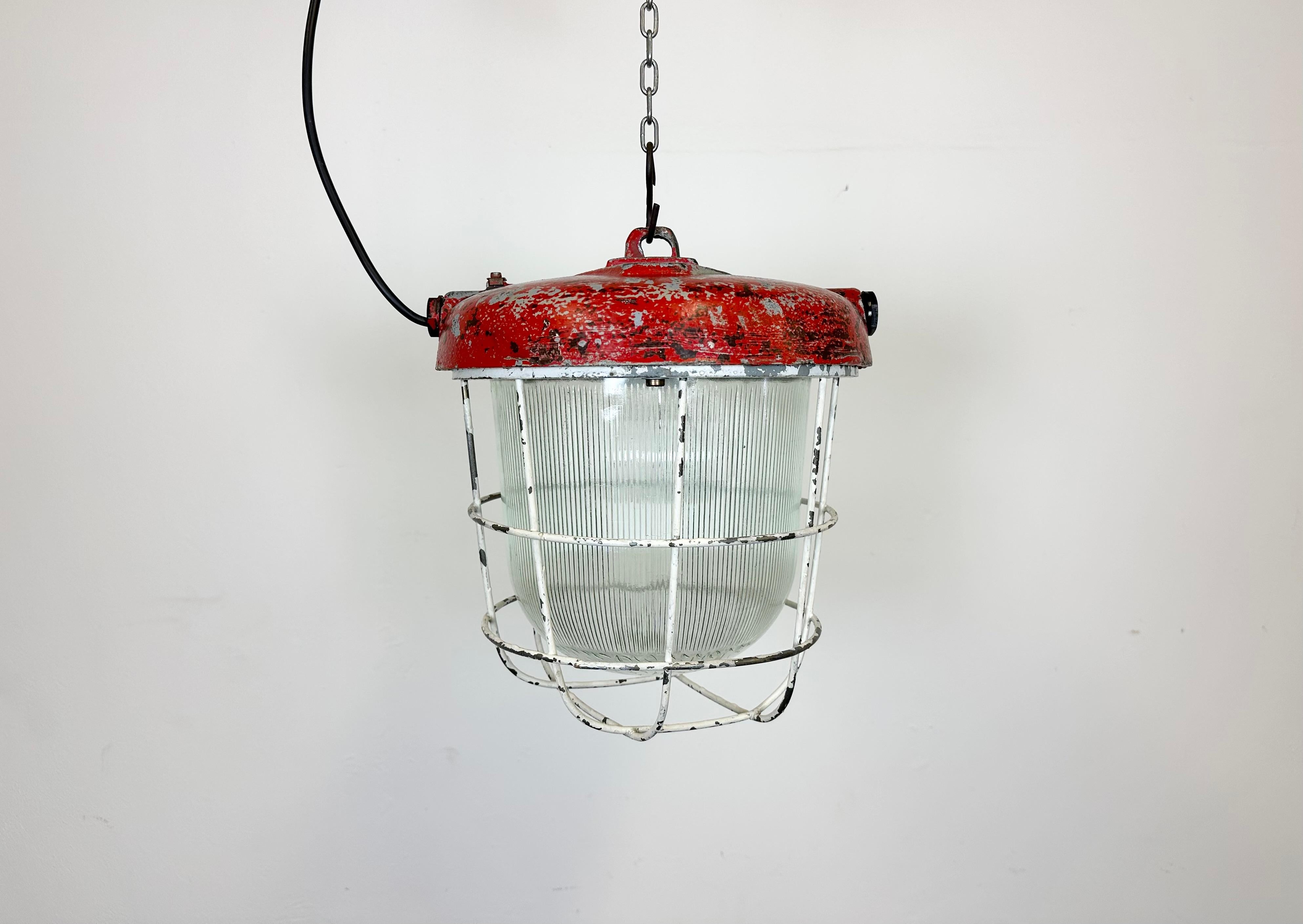 Industrial factory hanging lamp made by Polam Wilkasy in Poland during the 1960s.It features a cast iron top, a striped glass cover and an iron grid. The porcelain socket requires E 27 lightbulbs. New wire. The weight of the lamp is 8 kg.