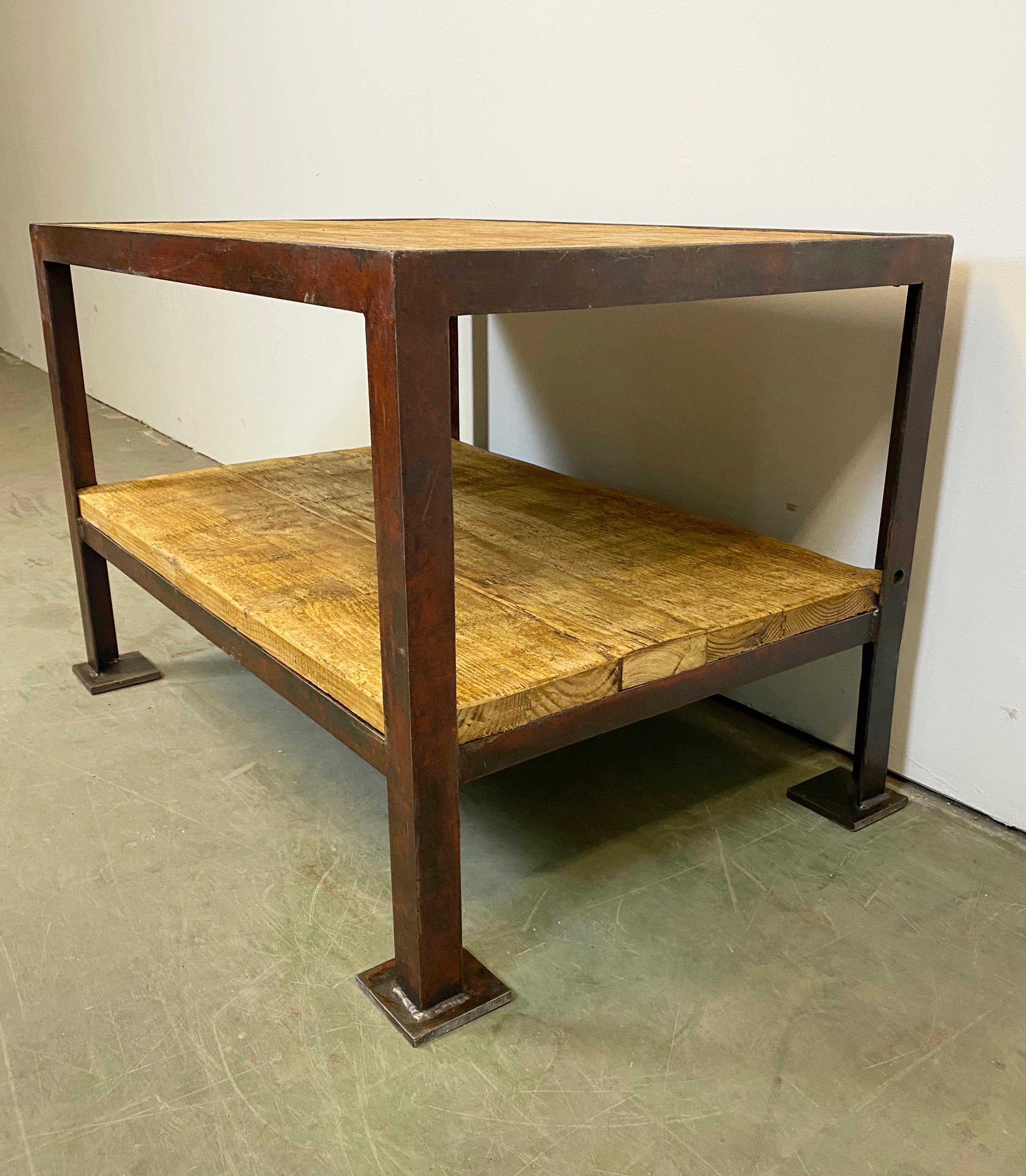 Vintage industrial coffee table from the 1960s. Made of wood and iron. It features a red iron construction and two solid wooden plates. The weight of the table is 52 kg.