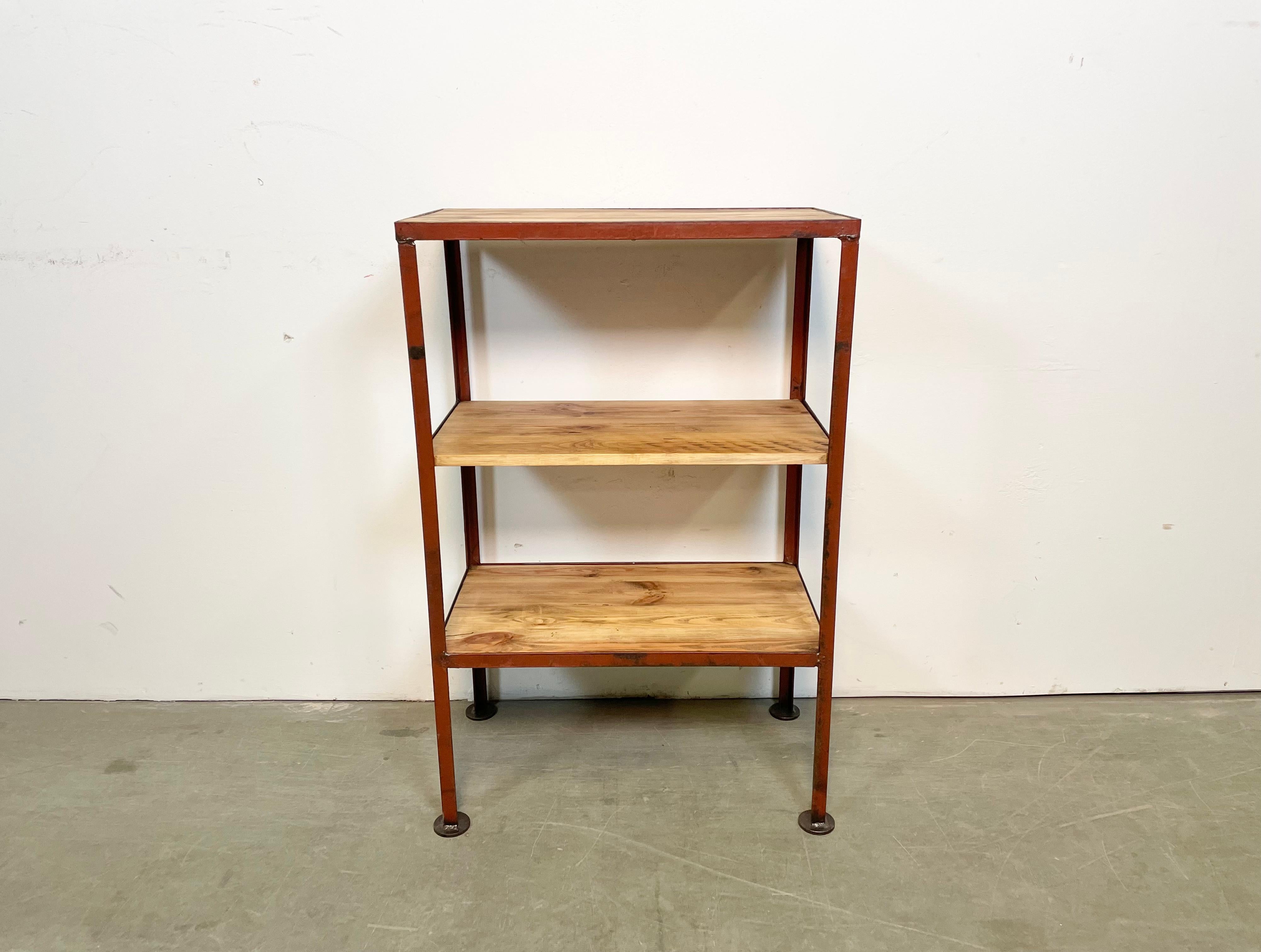 Industrial shelf from the 1960s. It features a red iron construction and three wooden shelves The weight of the shelf is 10 kg.
