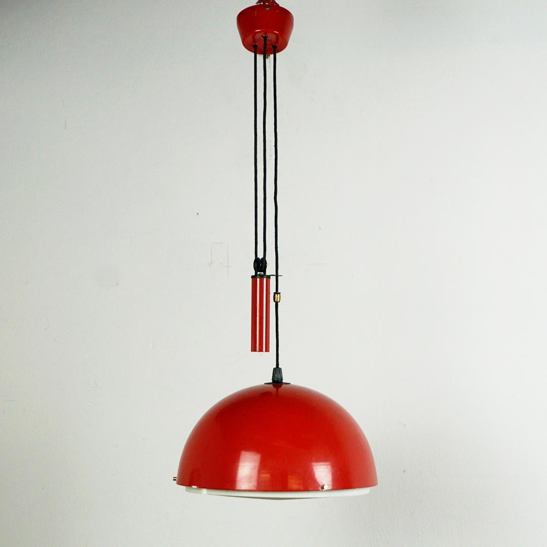 This charming Red lacquered Midcentury Modern pendant lamp with counterweight has been designed and produced in Italy in the 1960s. It features a red lacquered shade, weight and ceiling cap and brass fittings. On the underside it has a plastic shade