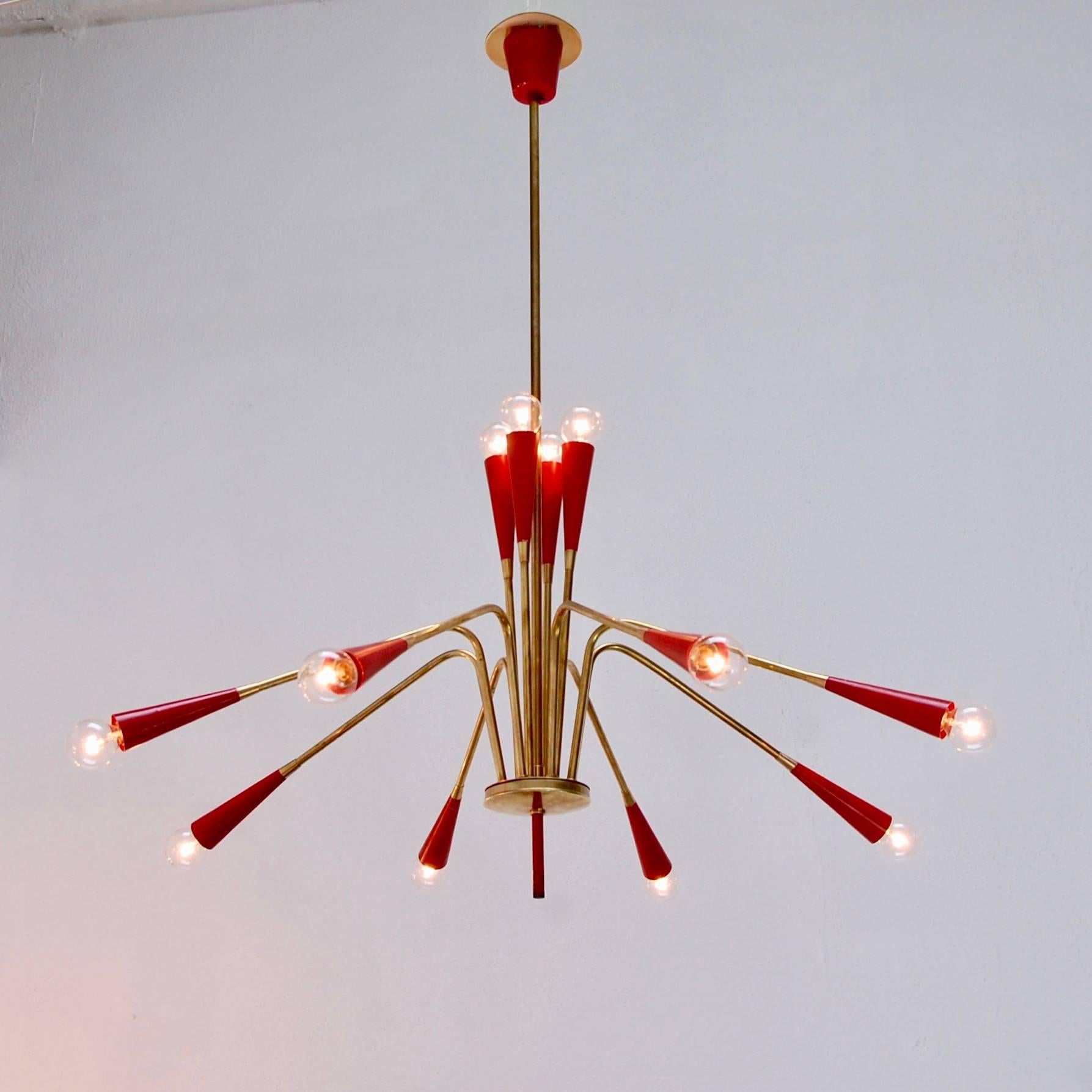 Stunning twelve-light Italian Sputnik light fixture from the 1950s. Original brass finish and painted aluminum finish in red. Rewired for use in the US. Candelabra based E12 sockets. 
Measures: Fixture height 18”
Diameter 30”
OAD 35”.
 