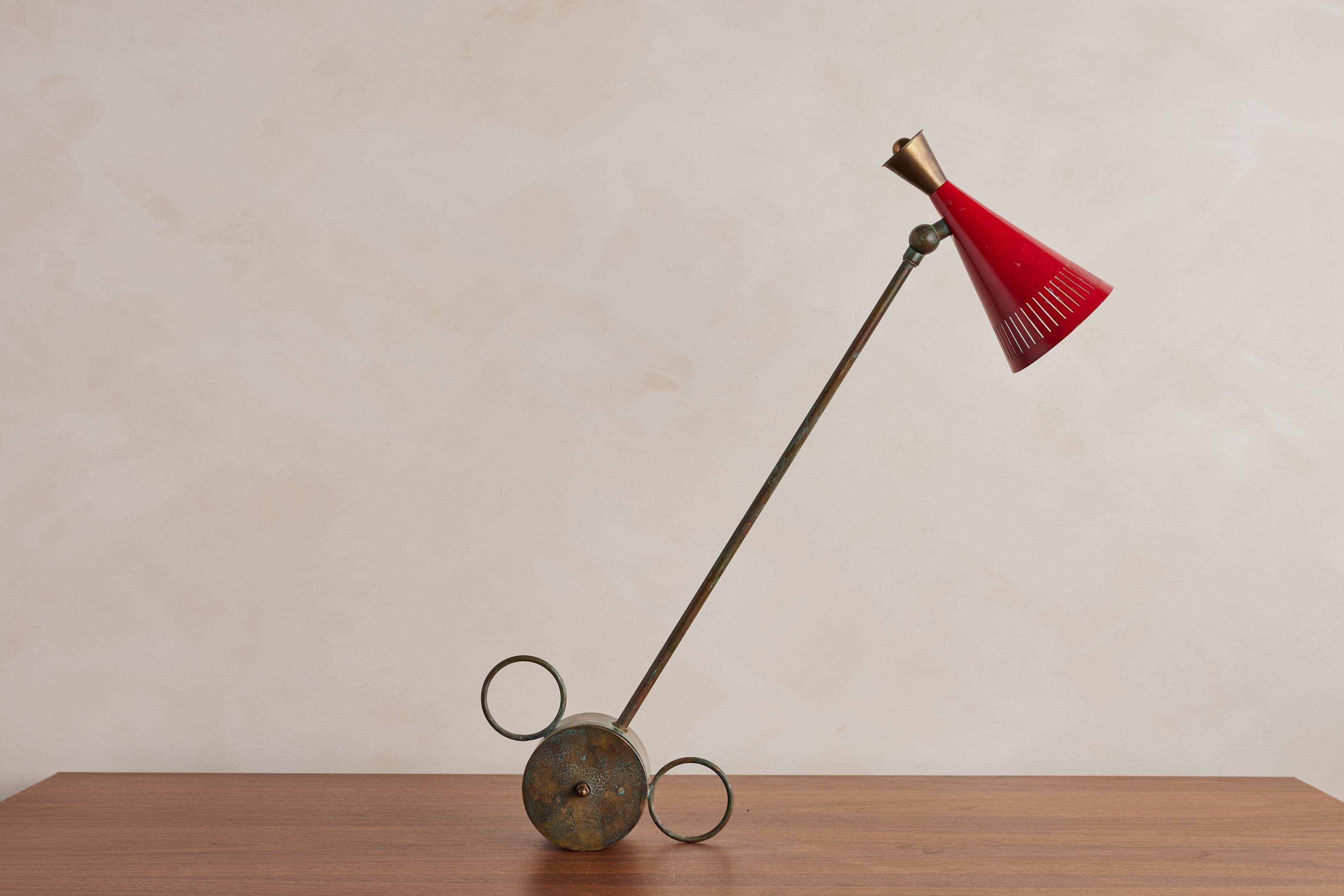 Unique Italian table lamp with red perforated shade and brass stem. 

Sits on a unique circular counterbalance brass base that rests in both directions

Wonderful patina 

Italy, 1950s

