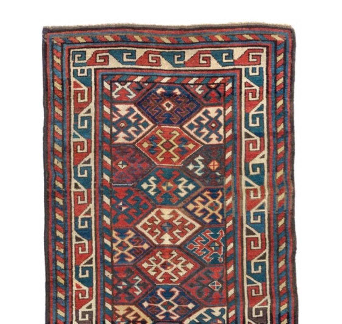 This is a hand knotted antique red ivory and navy blue tribal Caucasian Kazak rug, circa 1880-1900 measuring: 3 x 6 ft.

 