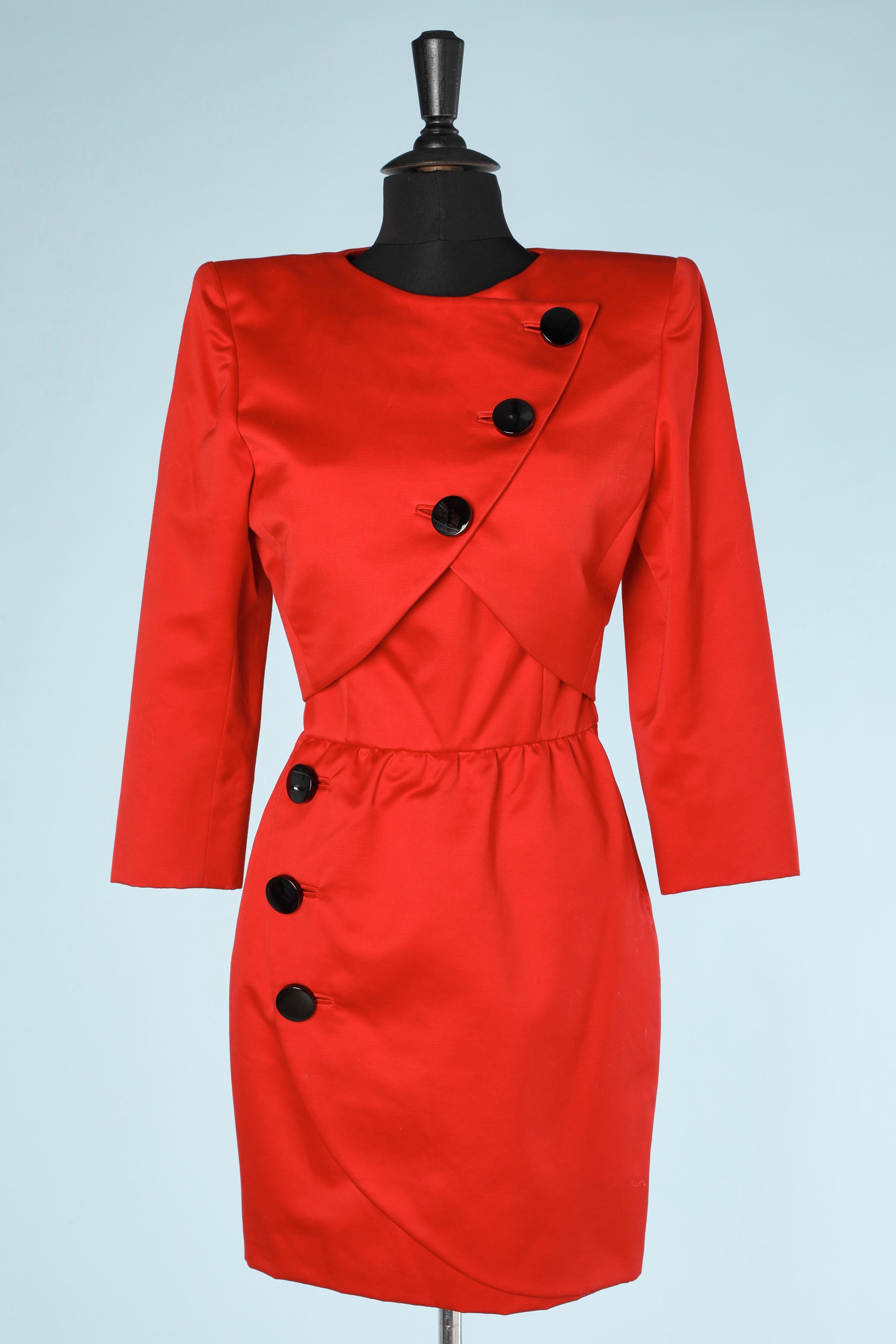 Red jacket and wrap bustier dress ensemble with black buttons. Main fabric composition: cotton . 
Shoulder pad. 
Dress is wraped, boned and padded on the chest. Zip on the left and hook&eye. Gros-grain inside the waist. 
SIZE M 