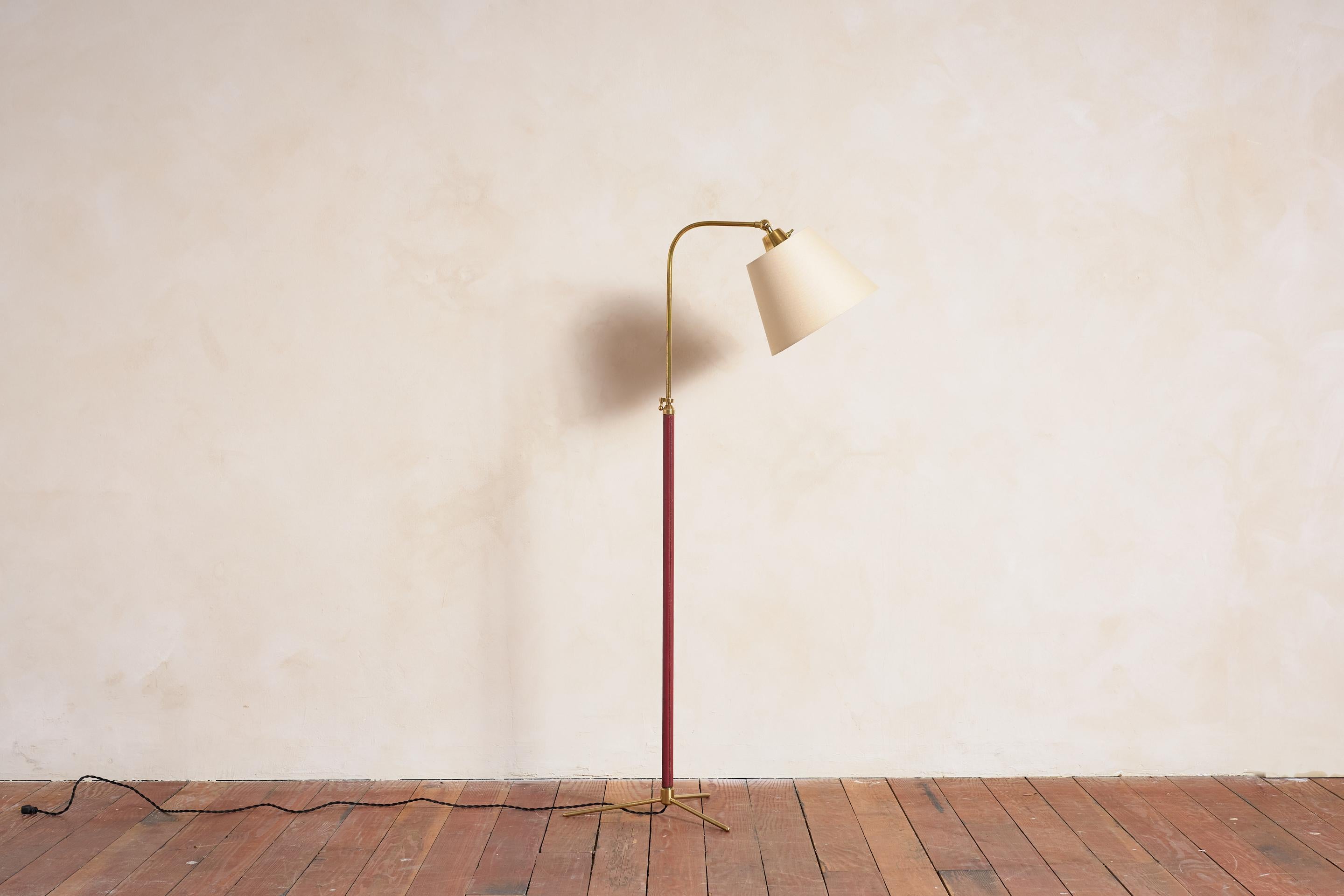 Beau lampadaire français de Jacques Adnet avec cuir rouge canneberge cousu à la main, coutures contrastées, base tripode en laiton et nouvel abat-jour en soie. 

Nouvellement recâblé.

La hauteur s'étend de 47
