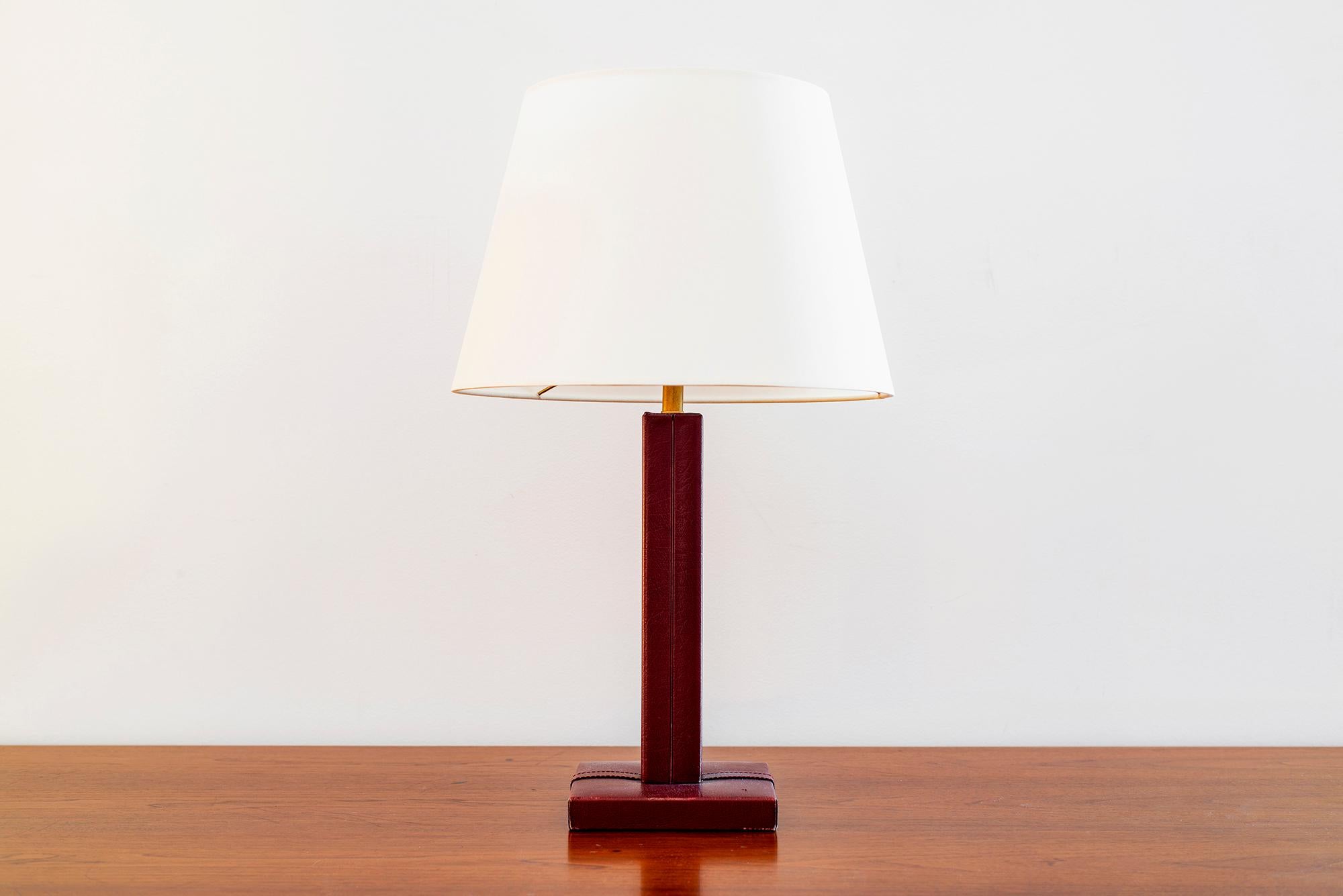 Jacques Adnet style table lamp. Aged red leather with signature contrast stitching. 
New silk shade and newly rewired.