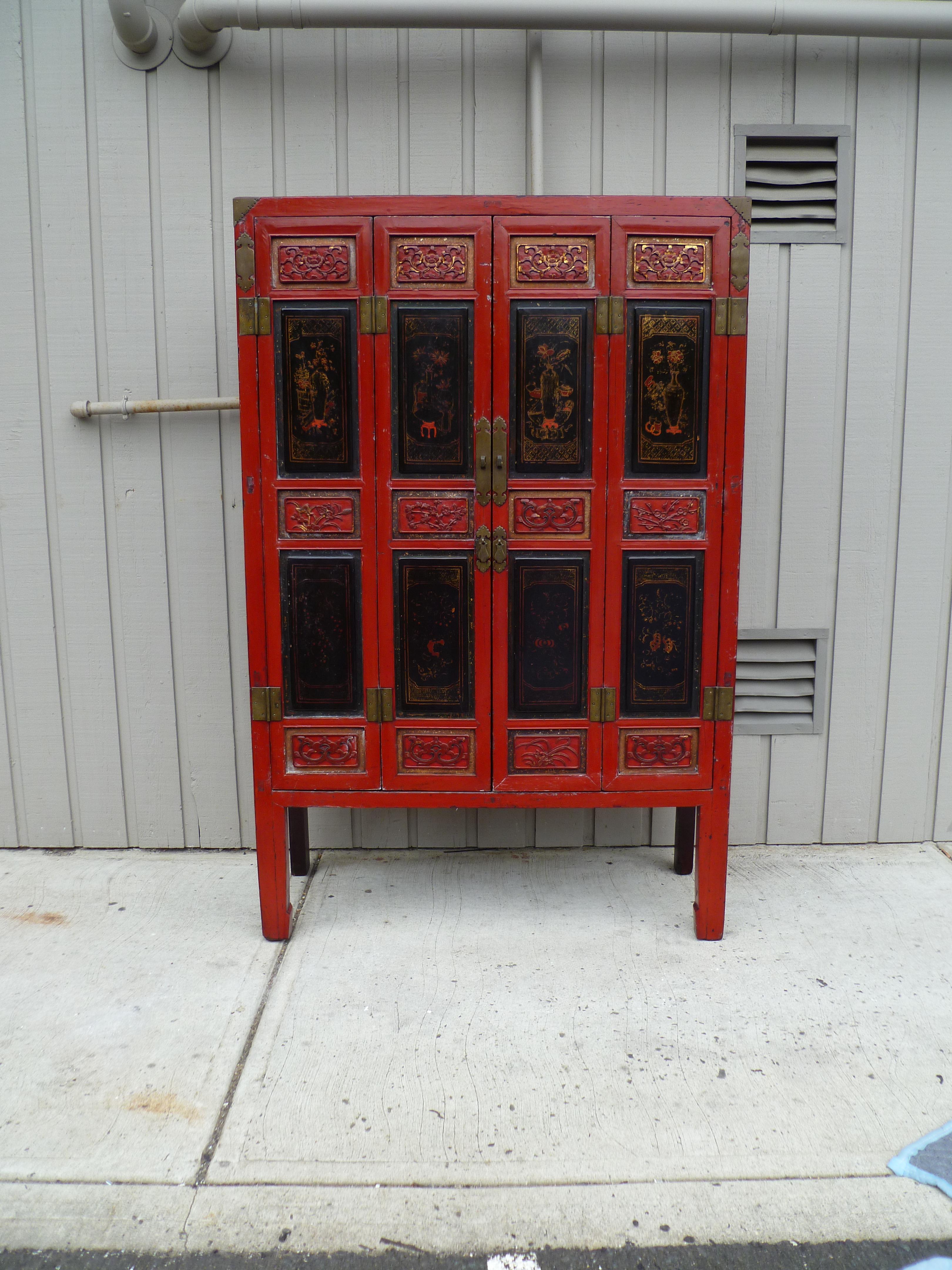 Rot lackierter Schrank mit Reliefschnitzerei und vergoldeten Türen.
Zweifach zu öffnende Türen, innen mit drei Einlegeböden, zwei der drei Einlegeböden sind herausnehmbar, innen drei Schubladen.