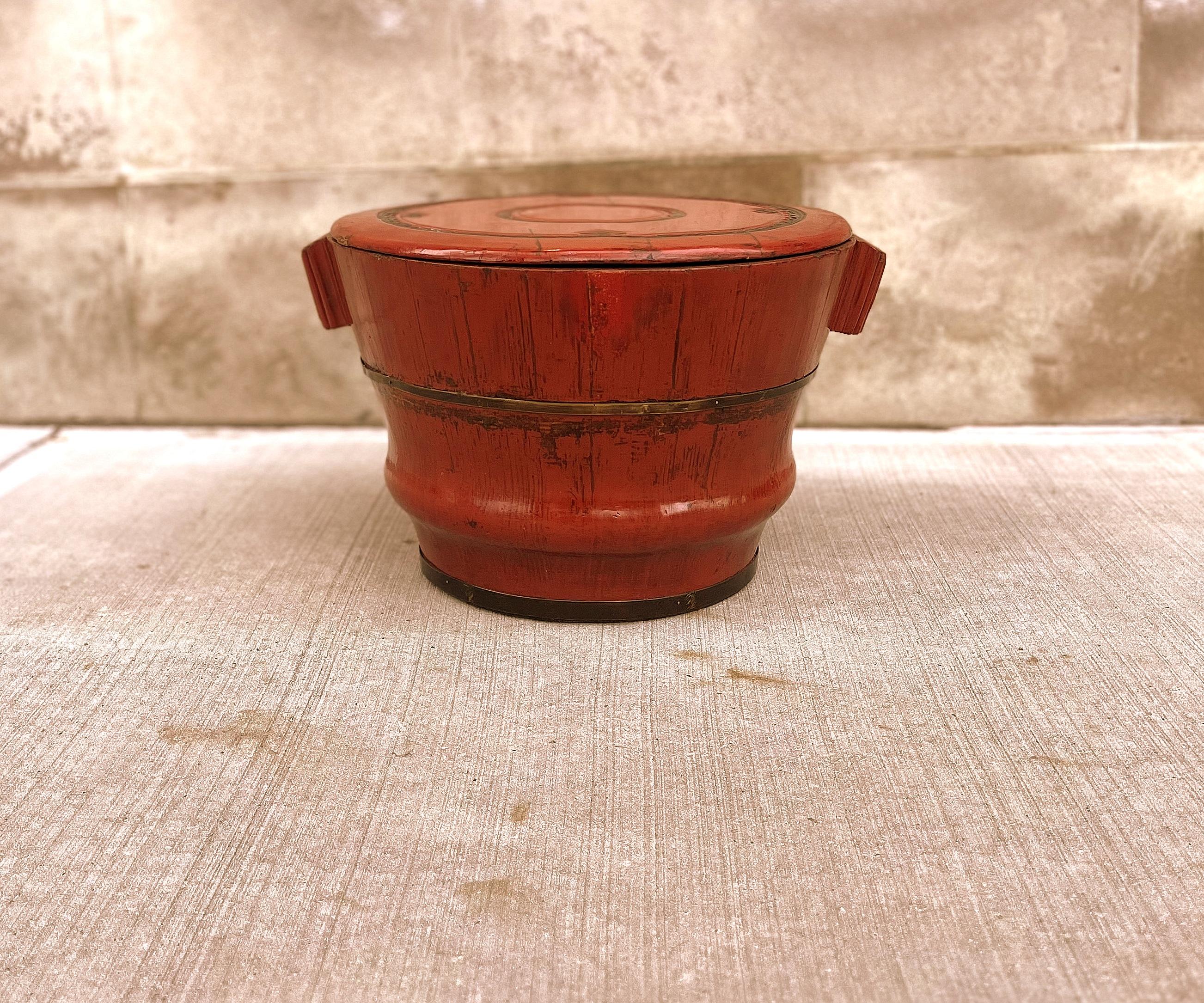 Antique red lacquer wood container was used to store rice or grains. The red lacquer container with two side short handles round shape, constructed with elm wood and body with metal bracket.  Top cover lid with relief carvings, well craftsmanship.