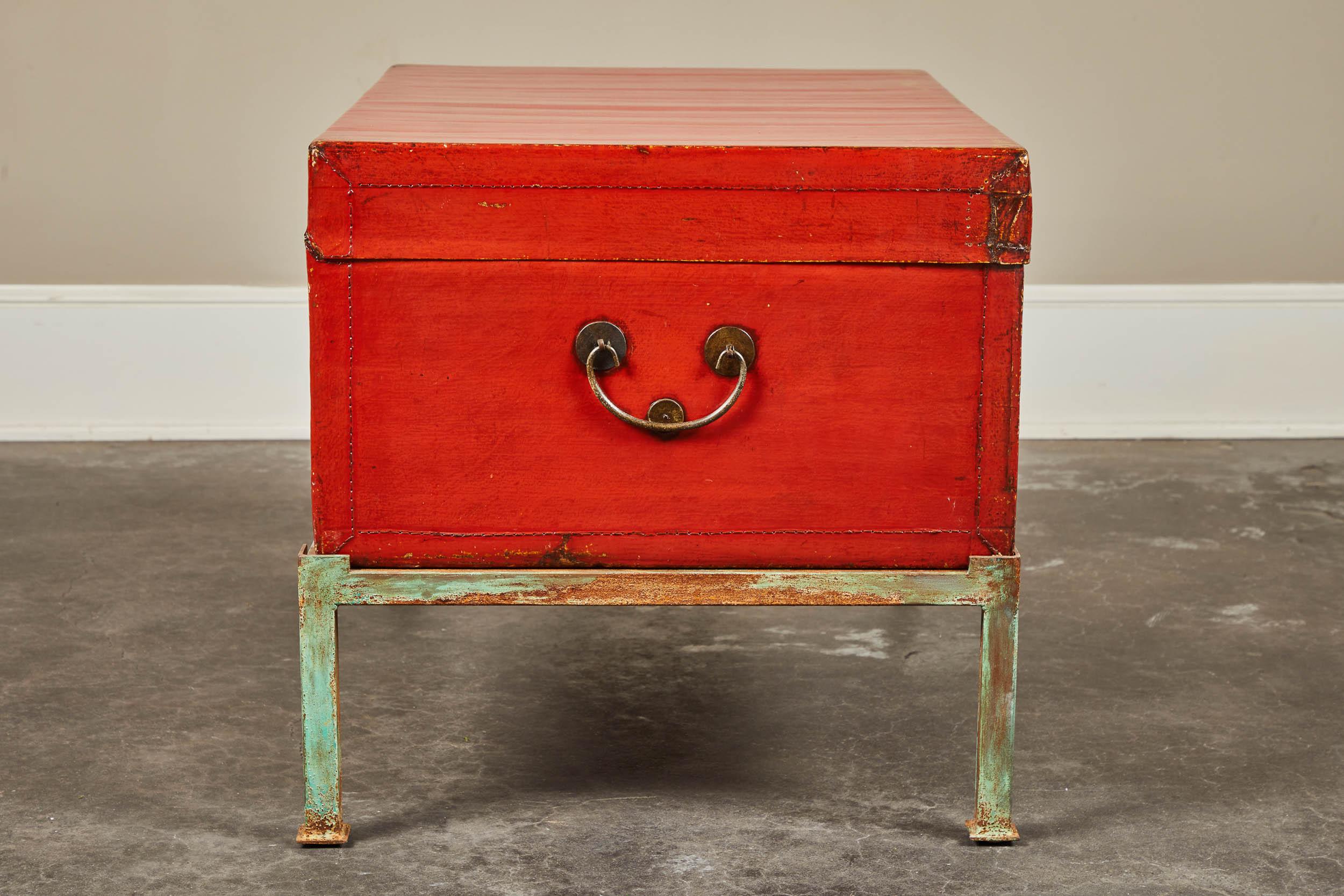 A 19th century pig-skin leather camphor trunk on newer stand. Red lacquer finish with front latch and side handles.
