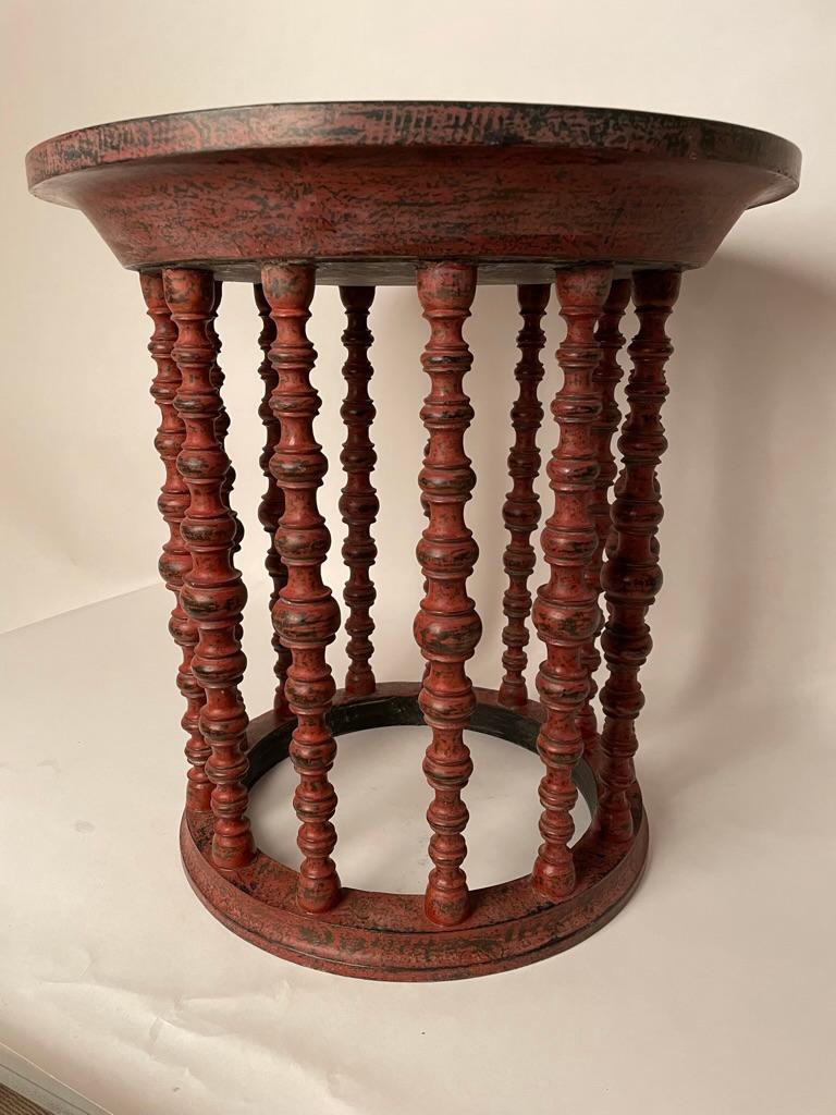 Very unusual and beautiful red and black lacquered round side table with 12 turned legs from Burma, now Myanmar. With a thick circular dish-form top. This piece in an antique with a very modern feel, a stunning addition to any interior. 
The