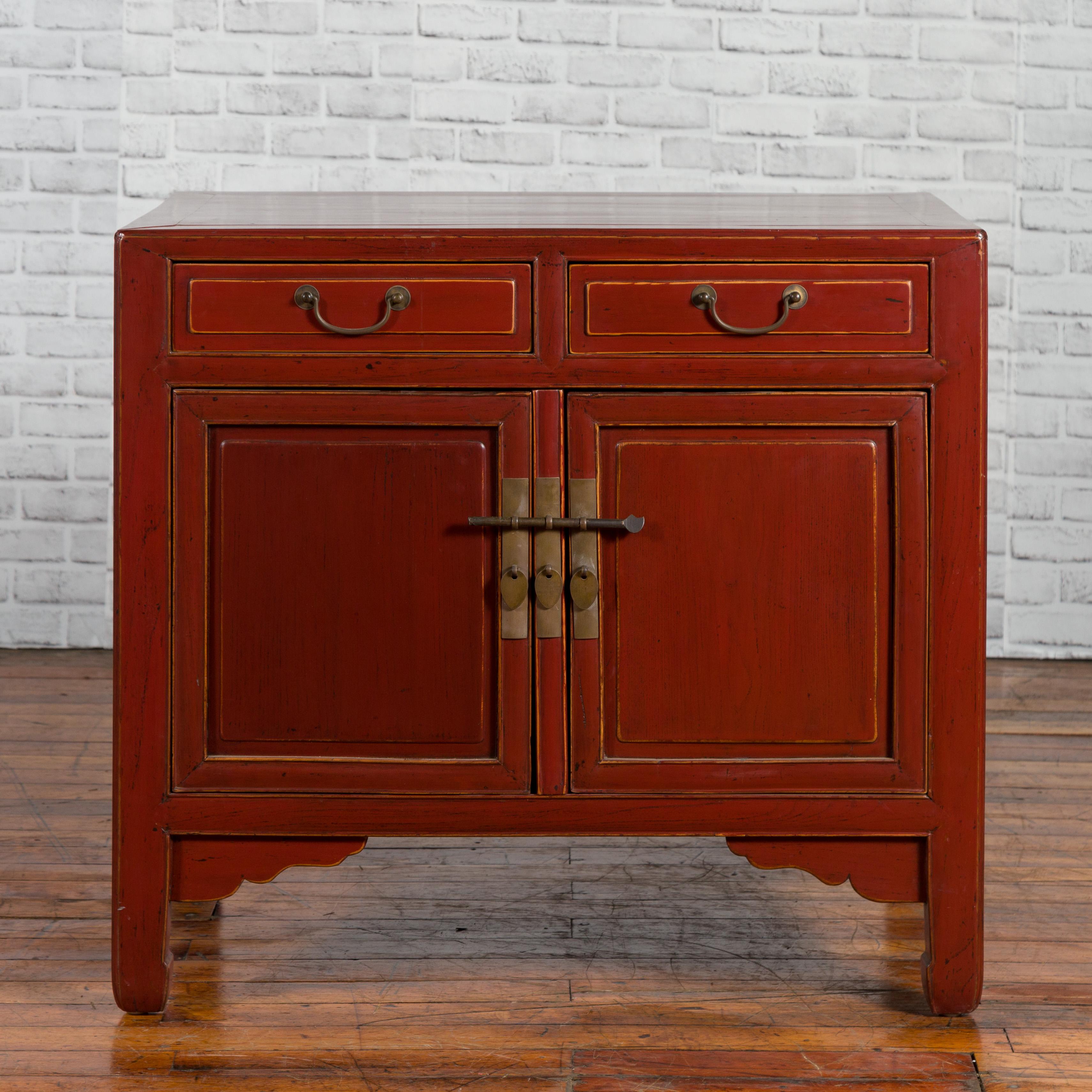 A Chinese Qing dynasty period red lacquered elm cabinet from the 19th century, with two drawers over two doors. Created in China during the Qing dynasty period, this elm cabinet attracts our attention with its red lacquered finish complimenting the