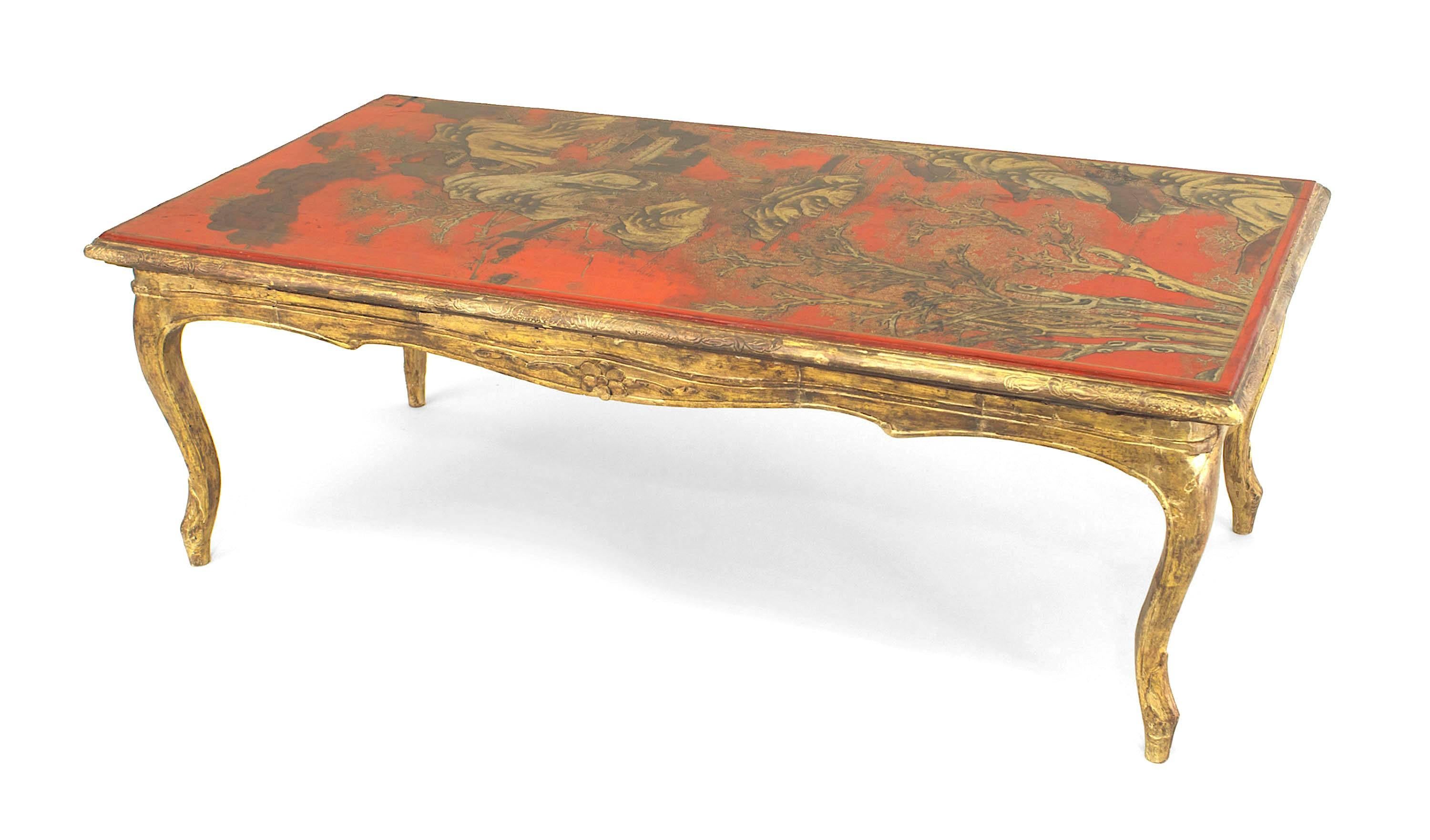 Table basse rectangulaire de style Louis XV français, à base de bois doré, supportant un plateau à décor de chinoiserie laqué rouge.