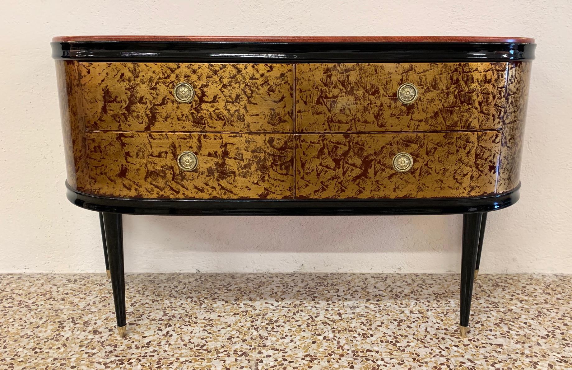 This dresser was produced in Italy in the 1940s.
Chest of drawers is red lacquered with a gold leaf decoration while the handles and details are in brass.
Top is in elegant red marble.