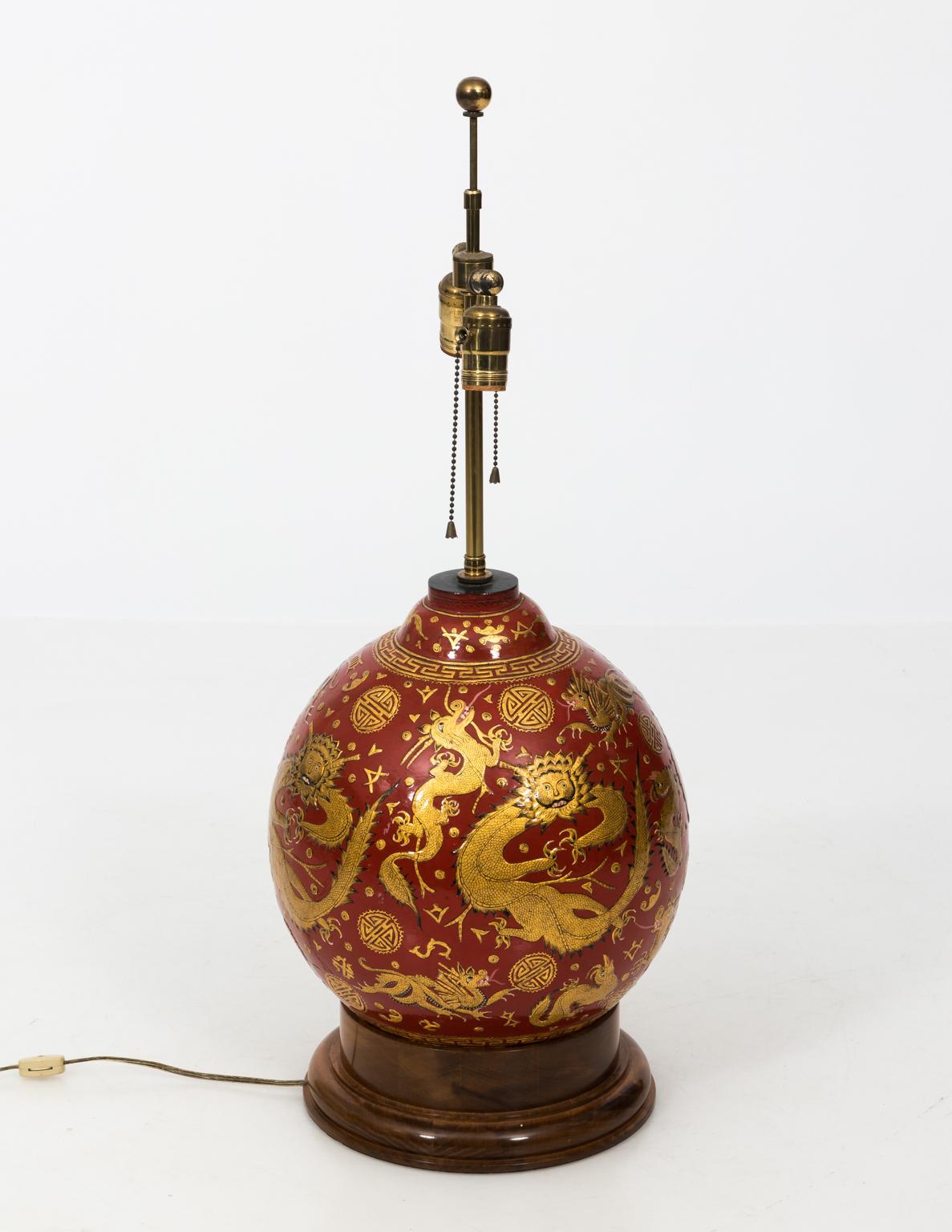 Late 20th century red lacquered Chinese lamp with carved gilded dragons. Wooden base. Shade not included.