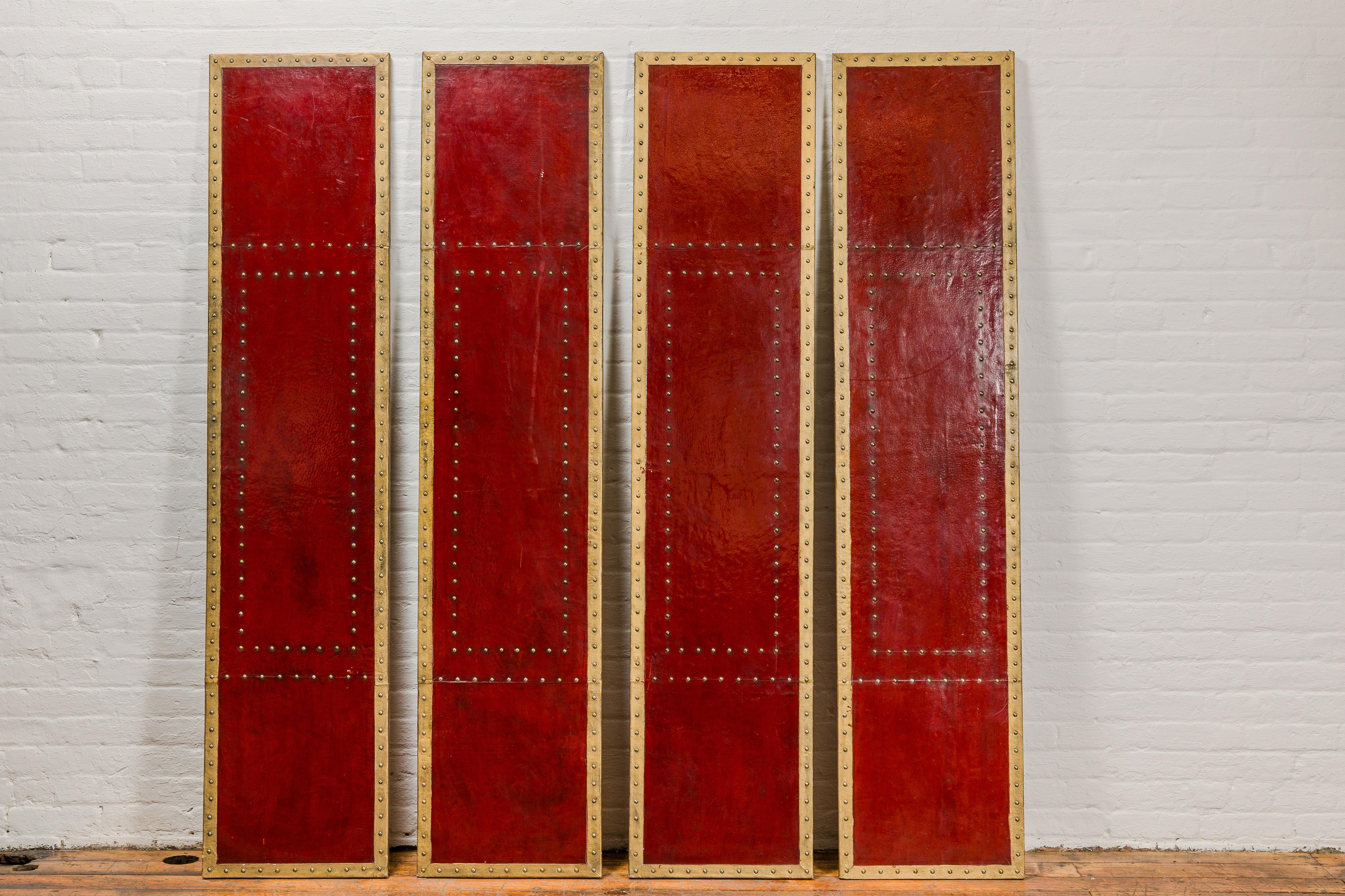 A set of four Chinese vintage red lacquered leather panels with brass nailhead accentuation. This set of four Chinese vintage panels exudes an aura of traditional elegance and cultural richness. Each panel is meticulously crafted from red lacquered