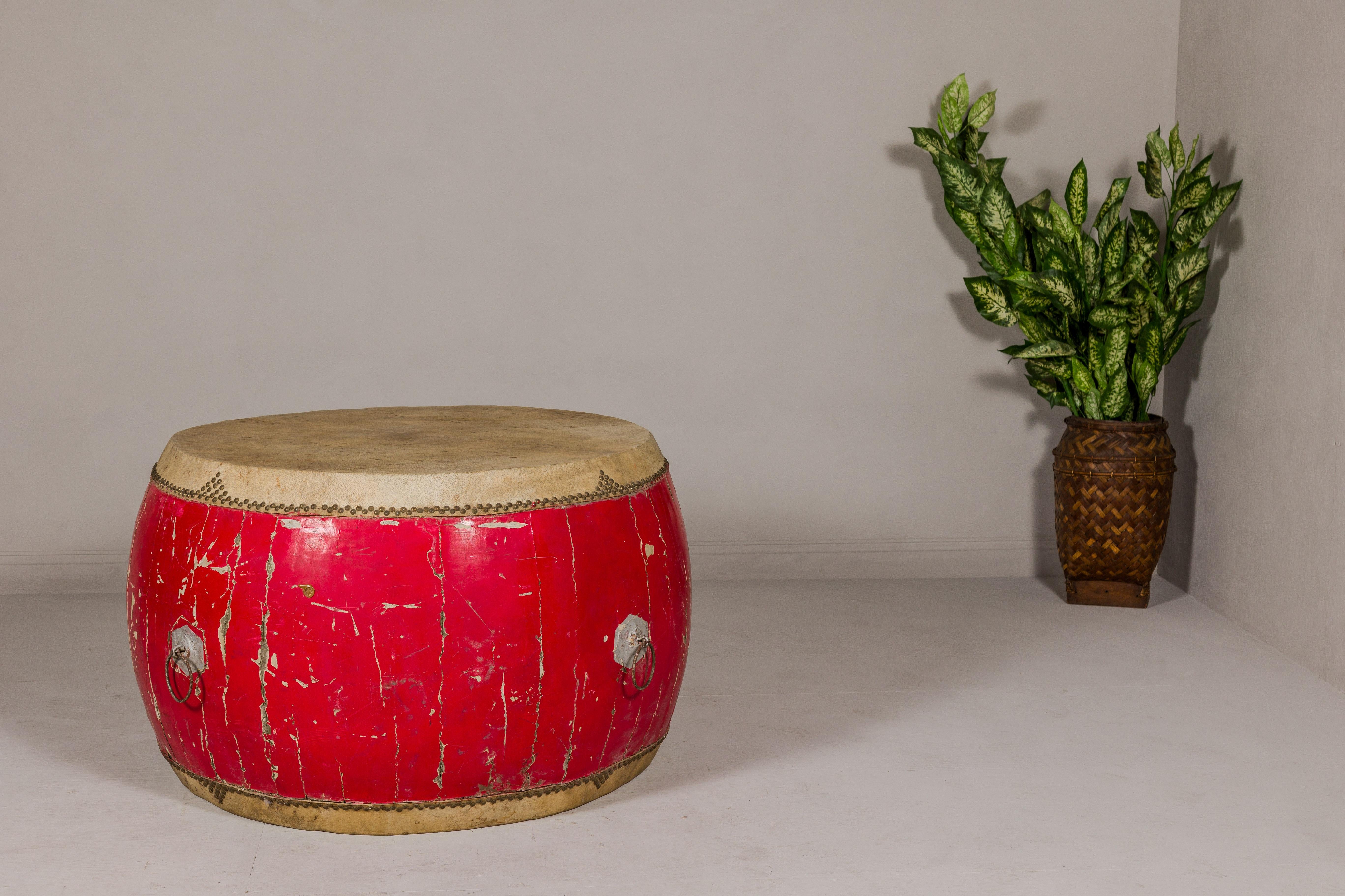 A late Qing Dynasty period red lacquered opera drum with brass studs, hide drumhead and four iron handles. This late Qing Dynasty period opera drum is a magnificent piece, steeped in history and bursting with character. Crafted with precision and