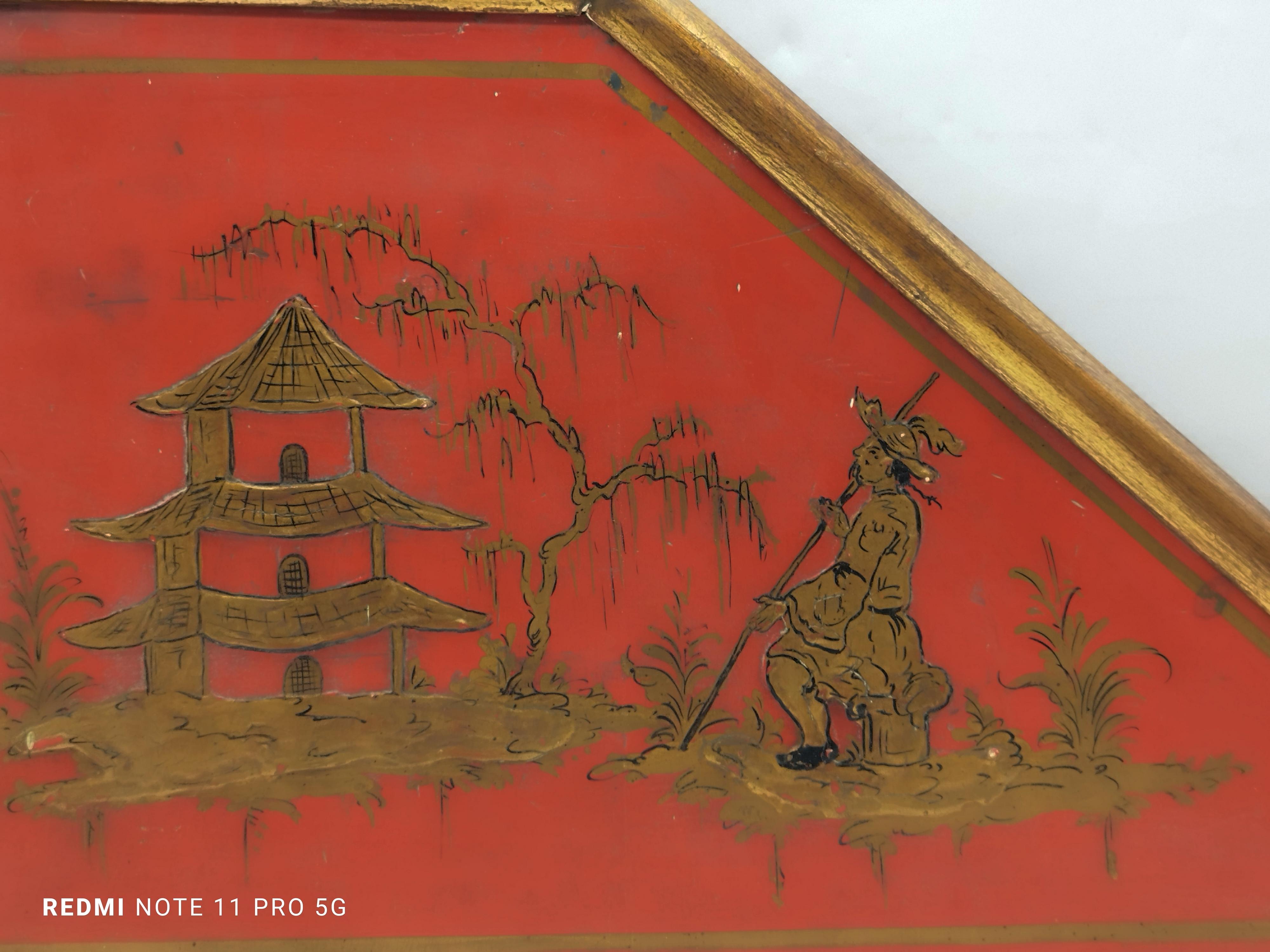 Decorative panel in red lacquered wood and gold frame, with Asian landscape depicting a pagoda and fisherman.