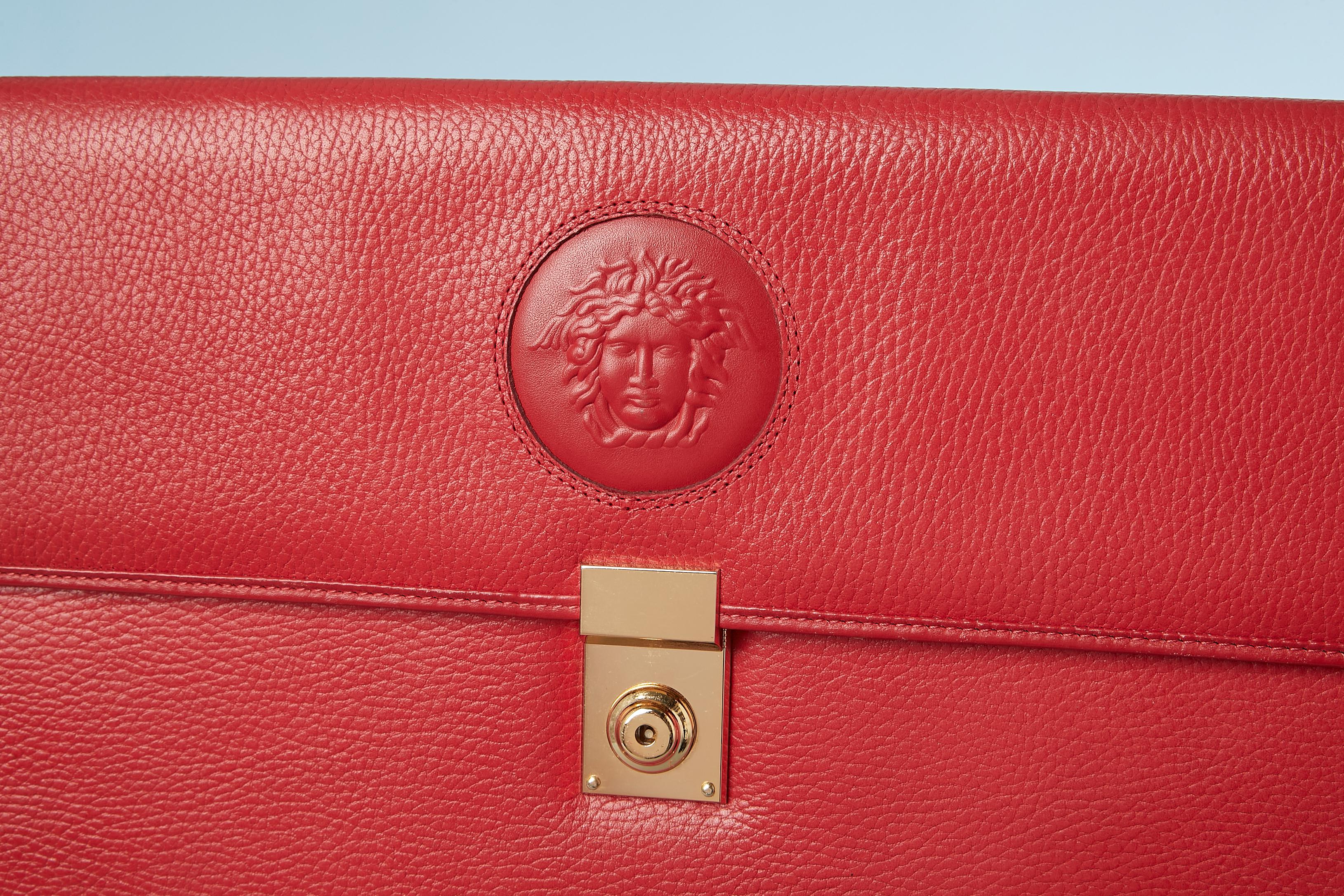 Red leather breifcase with Medusa embosset. Width:38 cm , height: 28 cm, depth: 5 cm . In leather with branded nylon lining. 
Lock ( no more keys) 
Flat pocket in the back. 