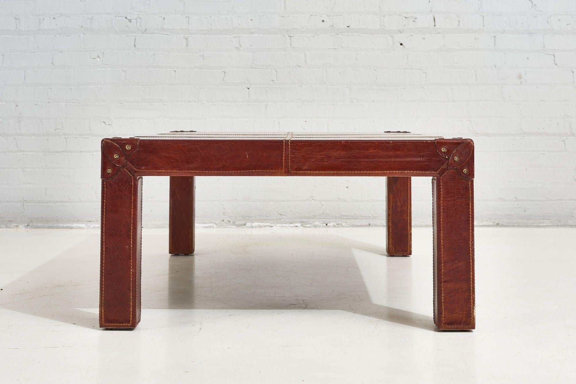 Red leather campaign coffee table, 1960. Table is made of saddle stitched red leather and has riveted double leather corners. Leather has a beautiful color and patina.