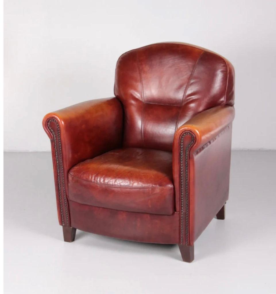 Red leather club chair by Studio Joris de Groot (unsigned) with original leather upholstery. Features semi roll-top arms, metal stud accenting, and sporty stitched accents along the chair and seat back. A classic piece with exquisite patina. 