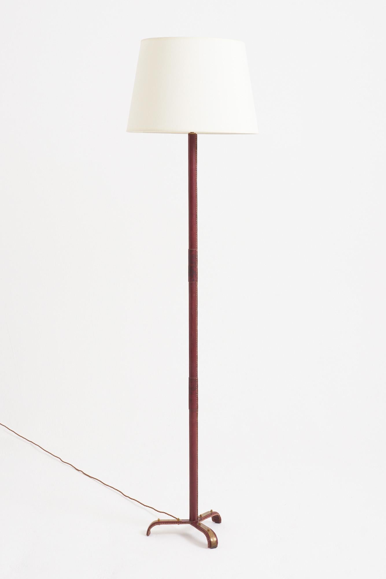 A saddle-stitched red leather floor lamp by Jacques Adnet (1900-1984)
France, mid 20th Century
With the shade: 177 cm high by 46 cm diameter 
Lamp base only: 150 cm high by 30 cm diameter (base)