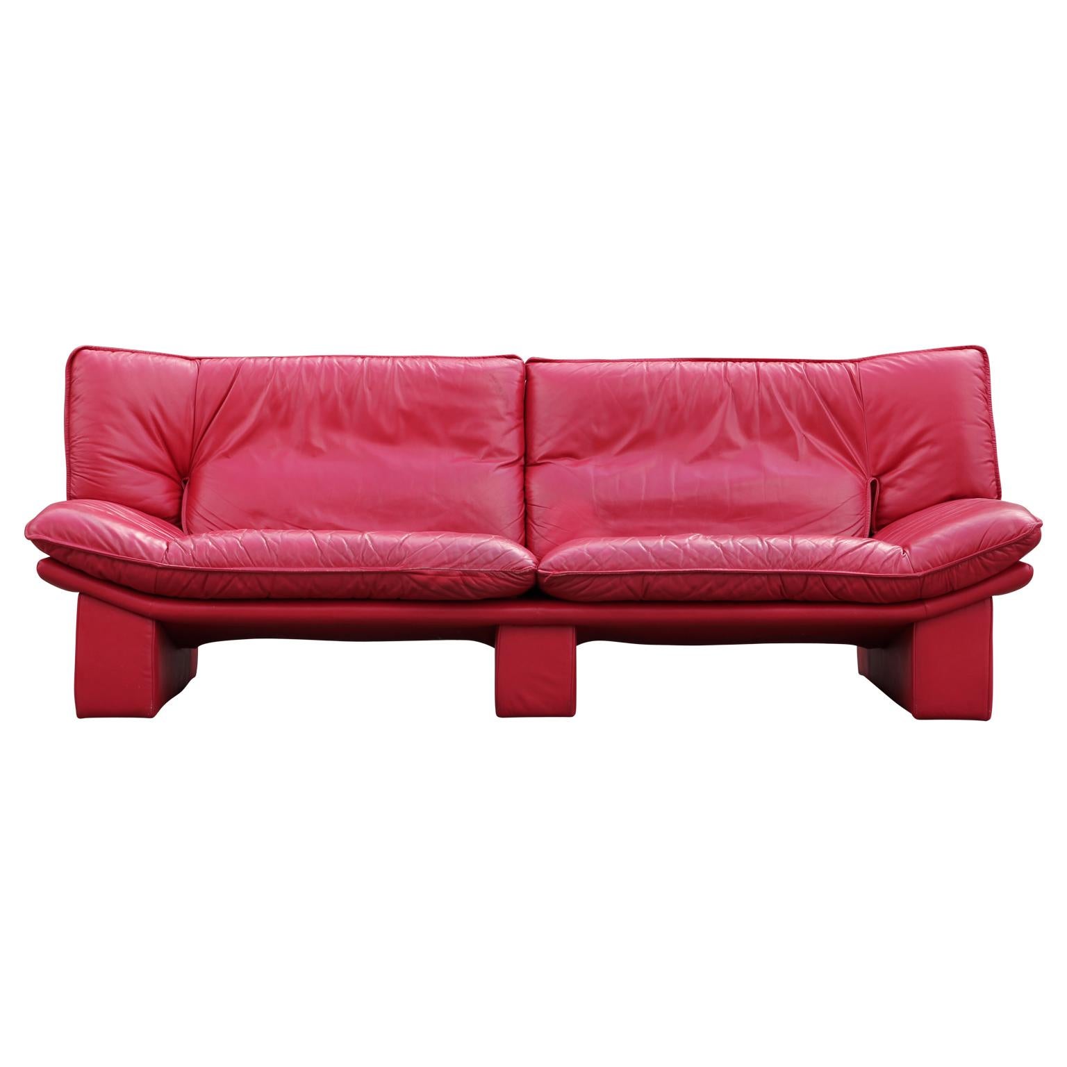 Modern bright red leather Italian sofa designed by Nicoletti Salotti. The couch has three feet that are upholstered in red leather. There is a rip in the seat and needs to be repaired or reupholstered.