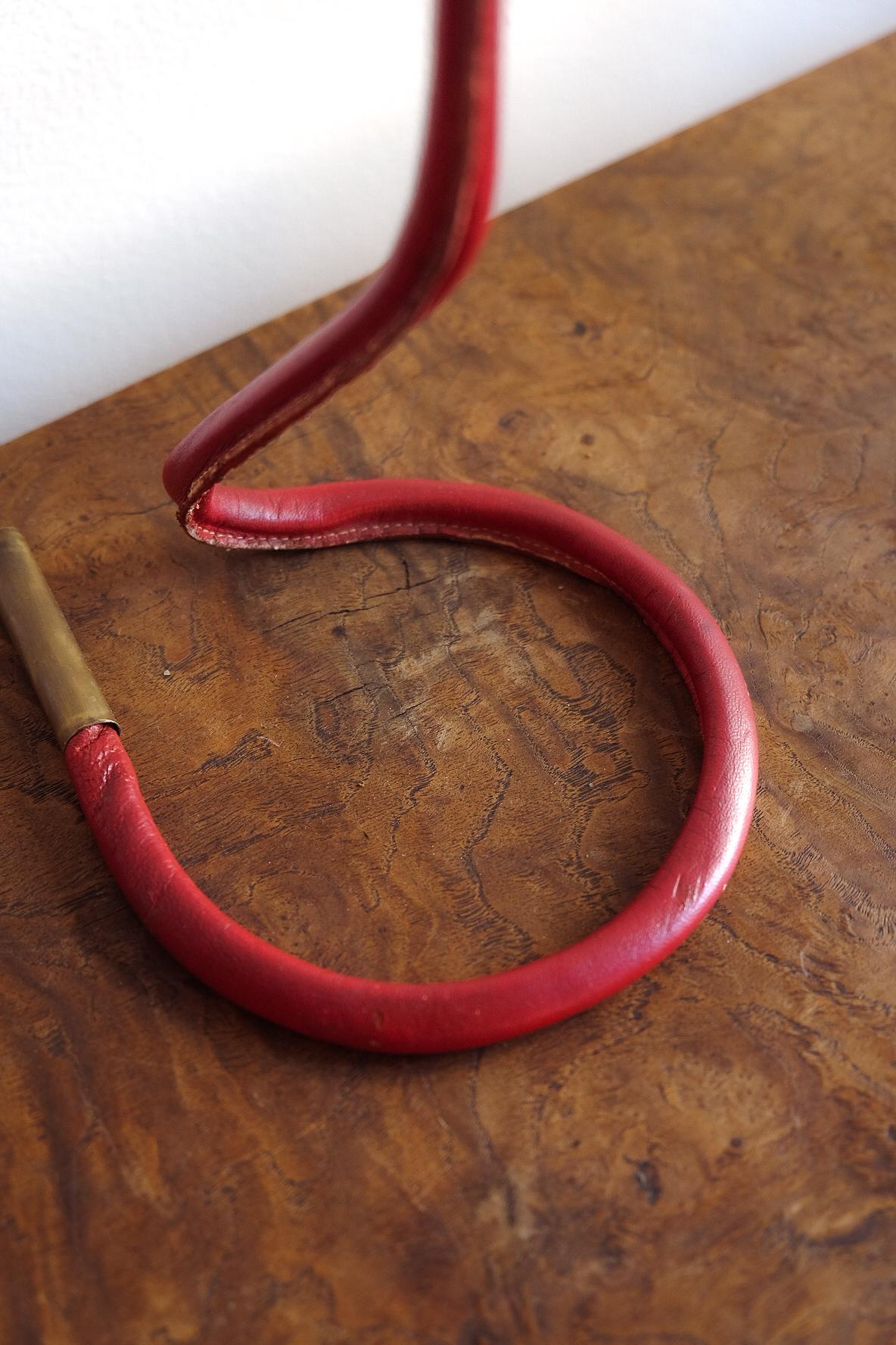 Bellissima lampada da tavolo in pelle rossa nello stile di Jacques Adnet. Base originale in pelle con paralume in carta rinnovato. 

Il paralume ha dettagli cuciti a mano.