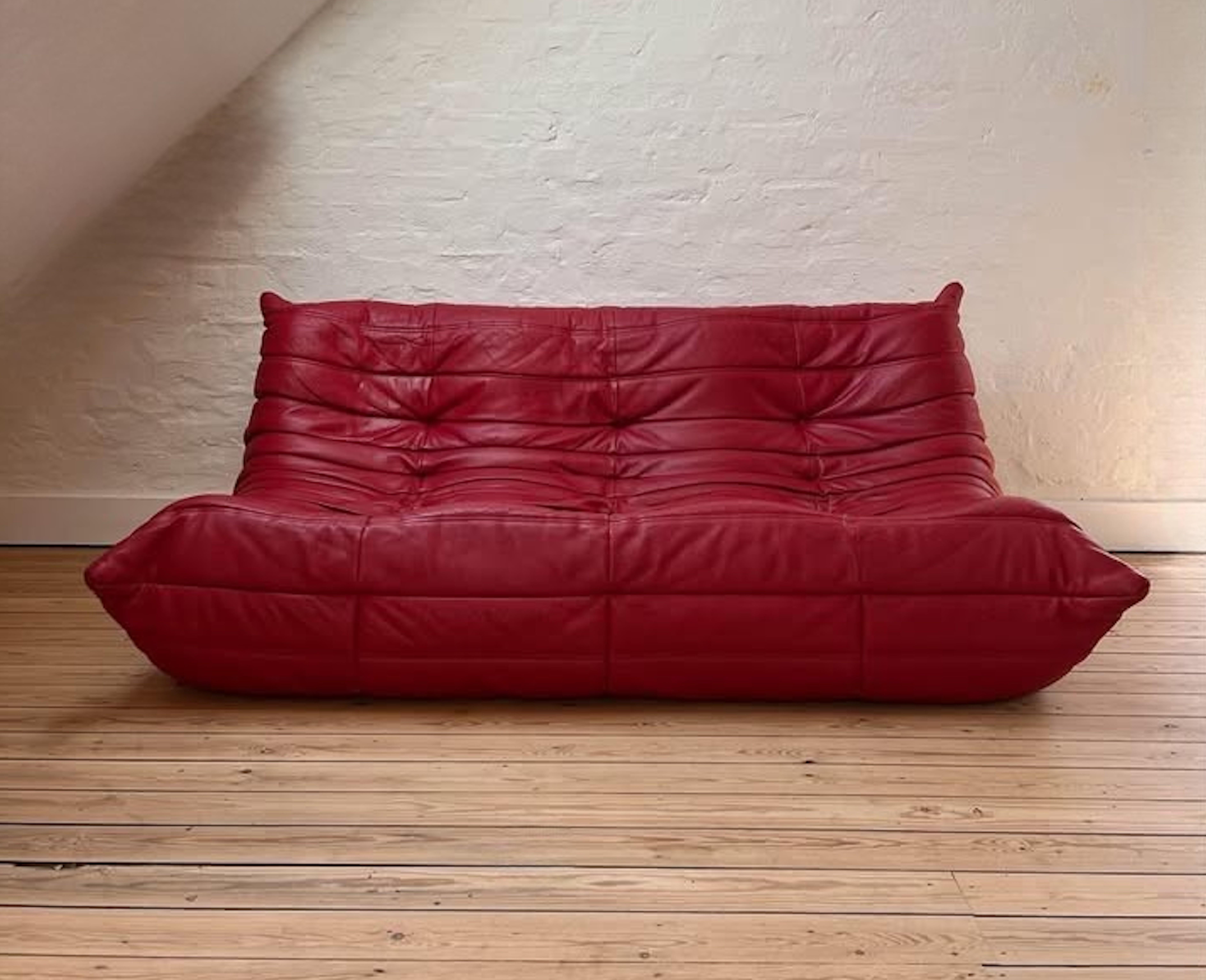 Un magnifique ensemble composé d'un canapé Togo en cuir rouge et de son ottoman, datant des années 1970. Le choix parfait pour ceux qui recherchent une pièce de design pointue, intemporelle et confortable. Elle restera l'une des créations les plus