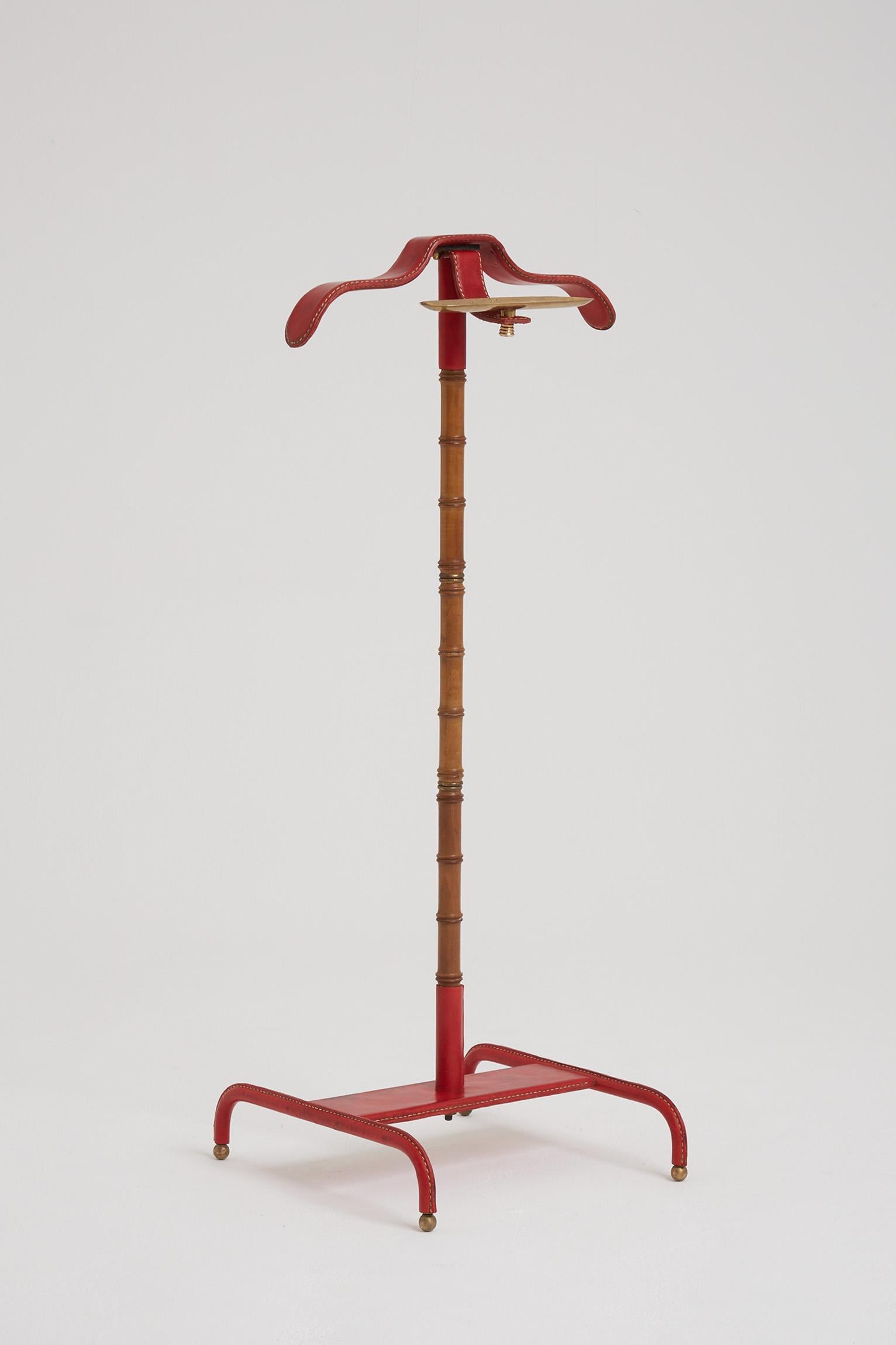 A red saddle stitched leather, brass mounted and stylised bamboo valet by Jacques Adnet (1900-1984).
France, Circa 1955.
