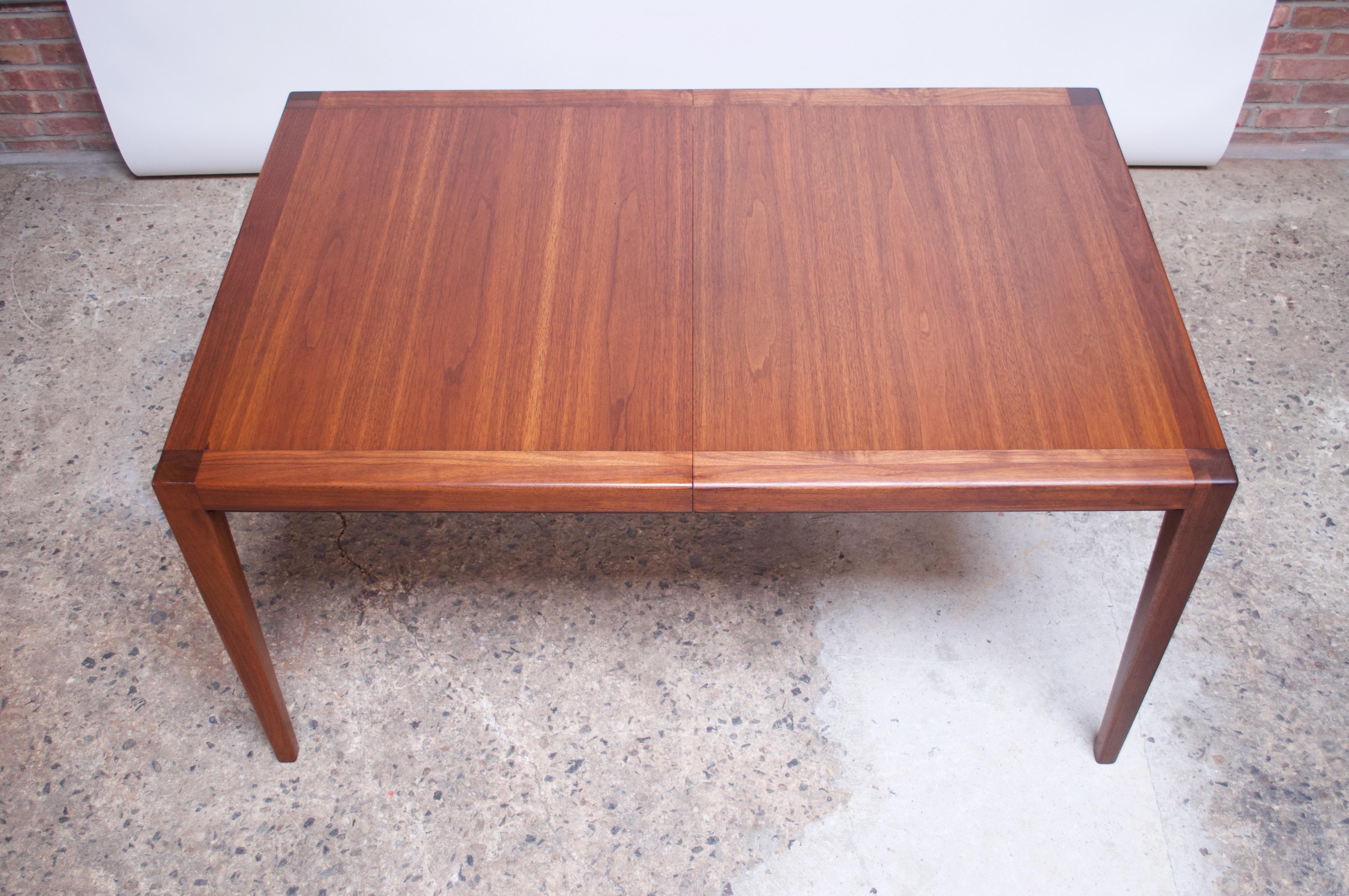1950s walnut dining table manufactured by Red Lion Table Company of Pennsylvania. Minimal, clean lines enhanced by dense, sculpted legs. Rails have been replaced to allow the table to pull open easily and seamlessly to insert the leaves (2 in total