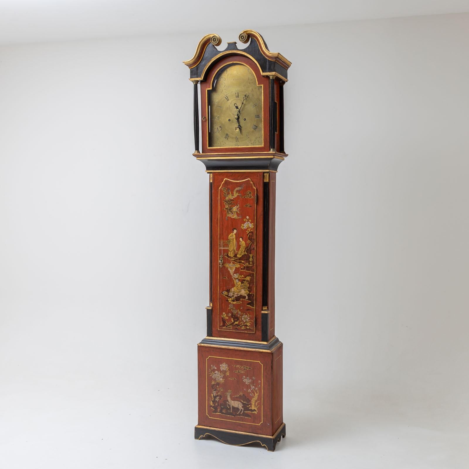  English grandfather clock with red lacquered case and gold chinoiserie decoration on the front. The movement with brass dial and Roman numerals is signed 
