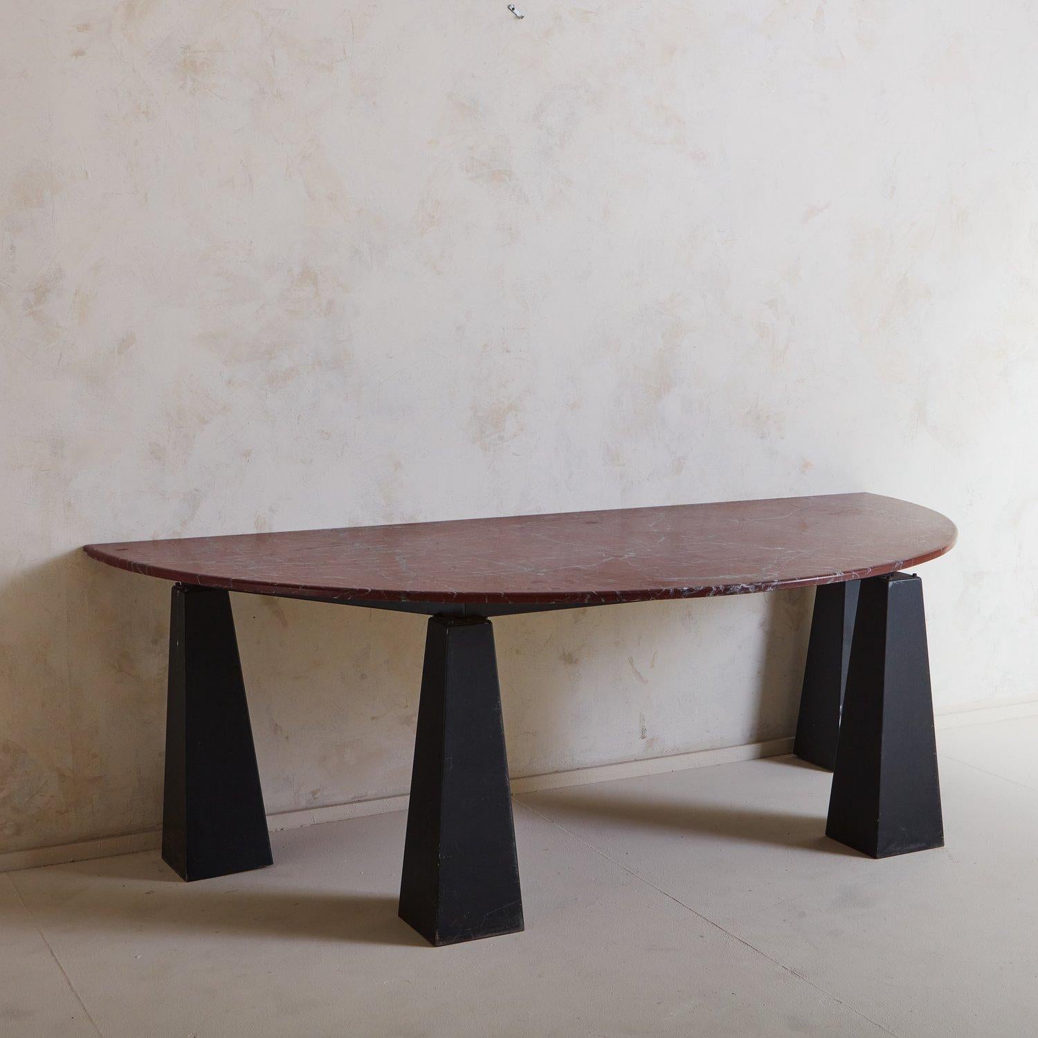 A stunning 1980s console table featuring a black lacquered iron base with four triangular block legs. This piece has a beautiful demilune marble top in a deep crimson hue with gray veining. ‘Engineering S.A.’ label on base. Sourced in France, 1980s.